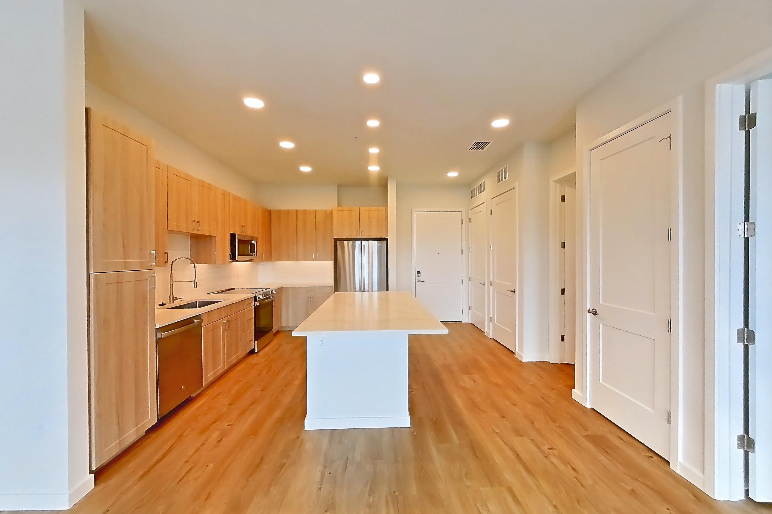 Living space with dishwasher, electric range, light countertops, light wood-finish flooring, oven/range, refrigerator, and stainless steel appliances, Apartment 454 at Lantower Bayside