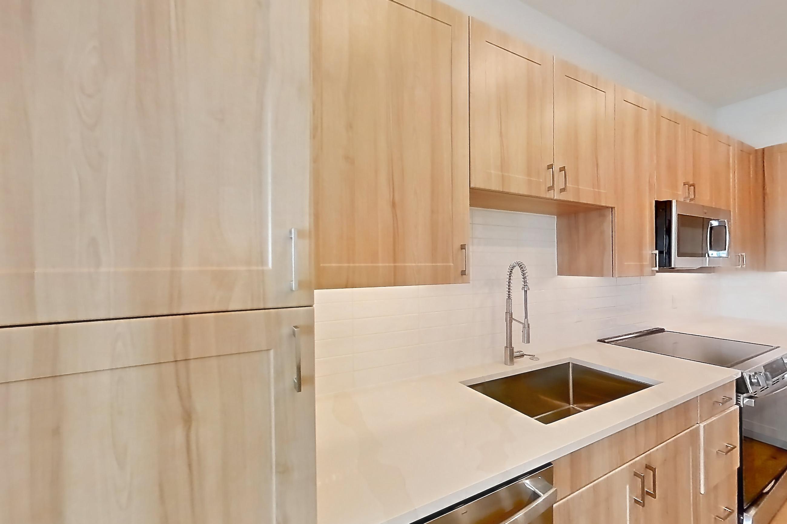 Kitchen with dishwasher, electric range, light countertops, light stone countertops, light wood-finish flooring, oven/range, refrigerator, and stainless steel appliances, Apartment 455 at Lantower Bayside