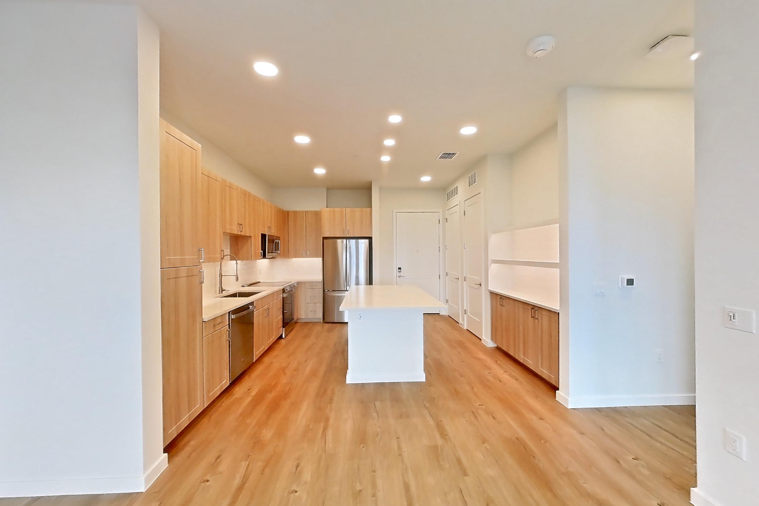 Living space with dishwasher, light countertops, light wood-finish flooring, oven/range, refrigerator, and stainless steel appliances, Apartment 457 at Lantower Bayside