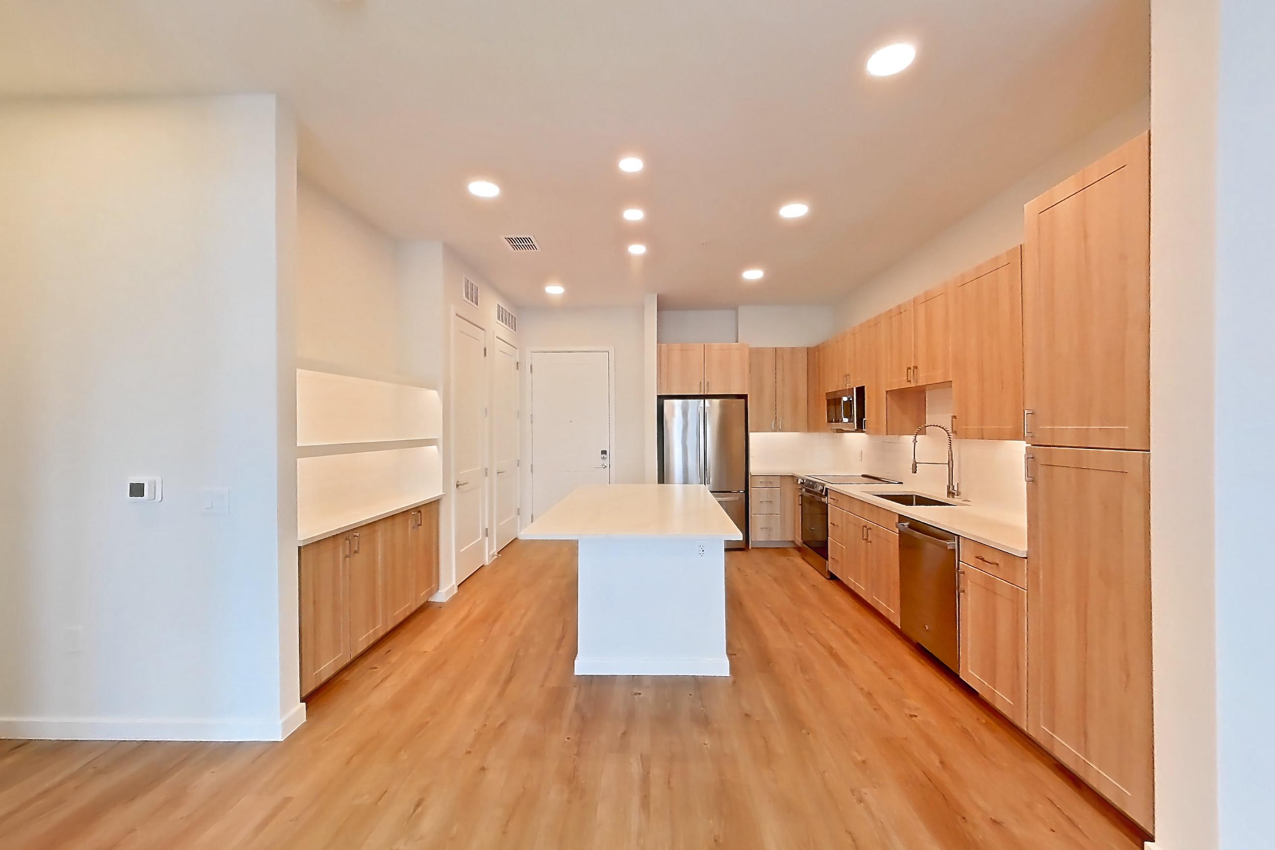 Living space with dishwasher, electric range, light countertops, light wood-finish flooring, oven/range, refrigerator, and stainless steel appliances, Apartment 458 at Lantower Bayside