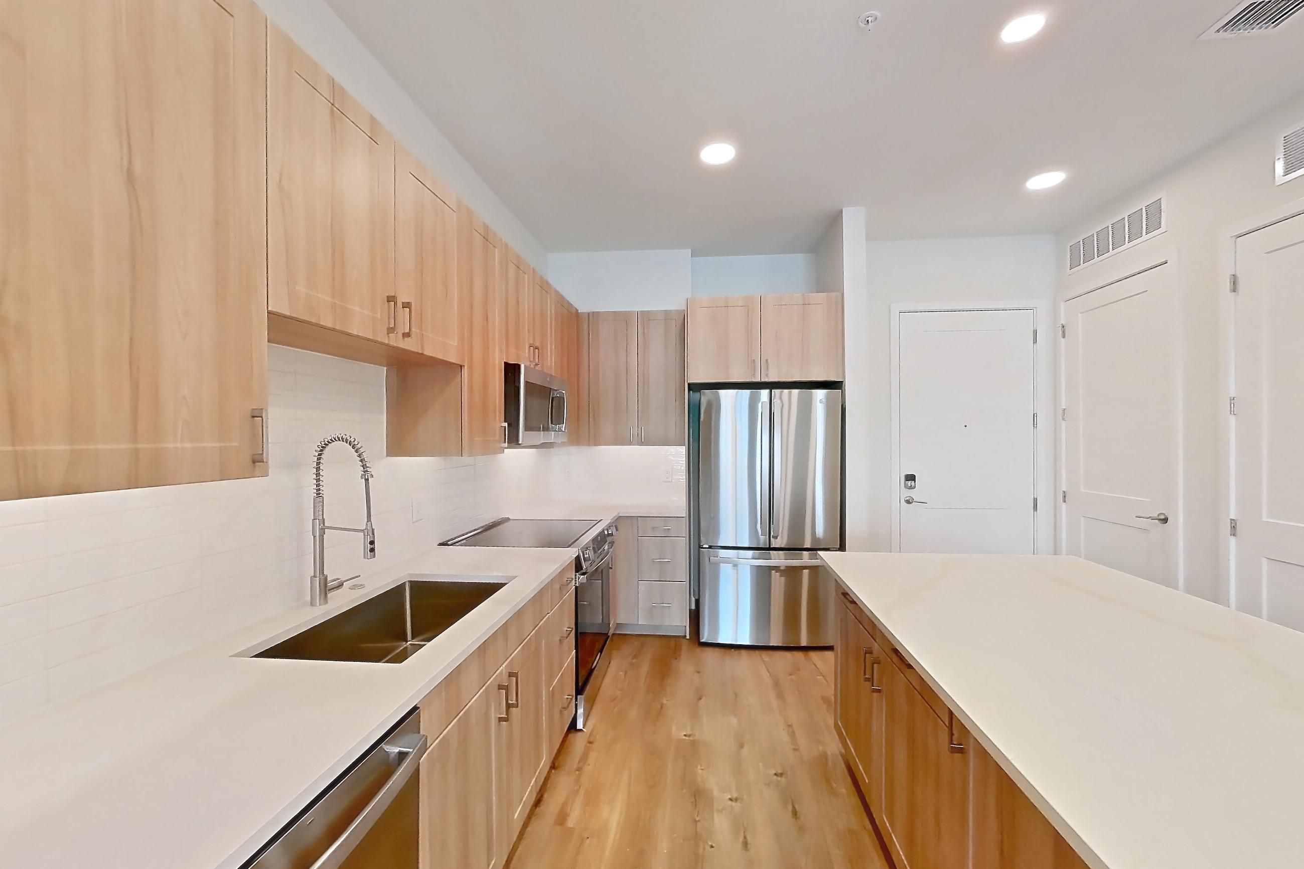 Kitchen with dishwasher, electric range, light stone countertops, light wood-finish flooring, microwave, oven/range, refrigerator, and stainless steel appliances, Apartment 460 at Lantower Bayside