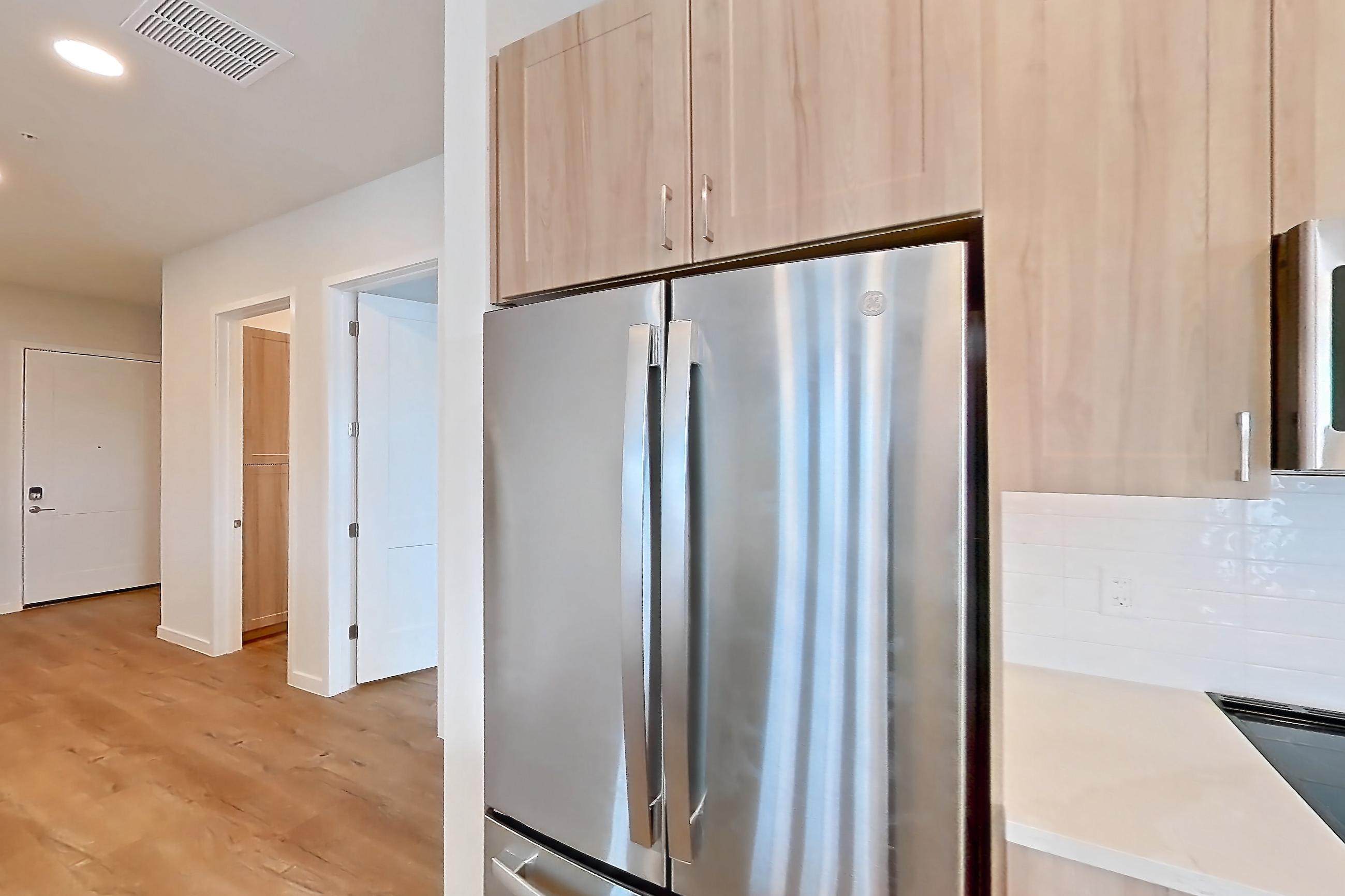 Kitchen with dishwasher, electric range, light countertops, light stone countertops, light wood-finish flooring, microwave, oven/range, refrigerator, and stainless steel appliances, Apartment 465 at Lantower Bayside