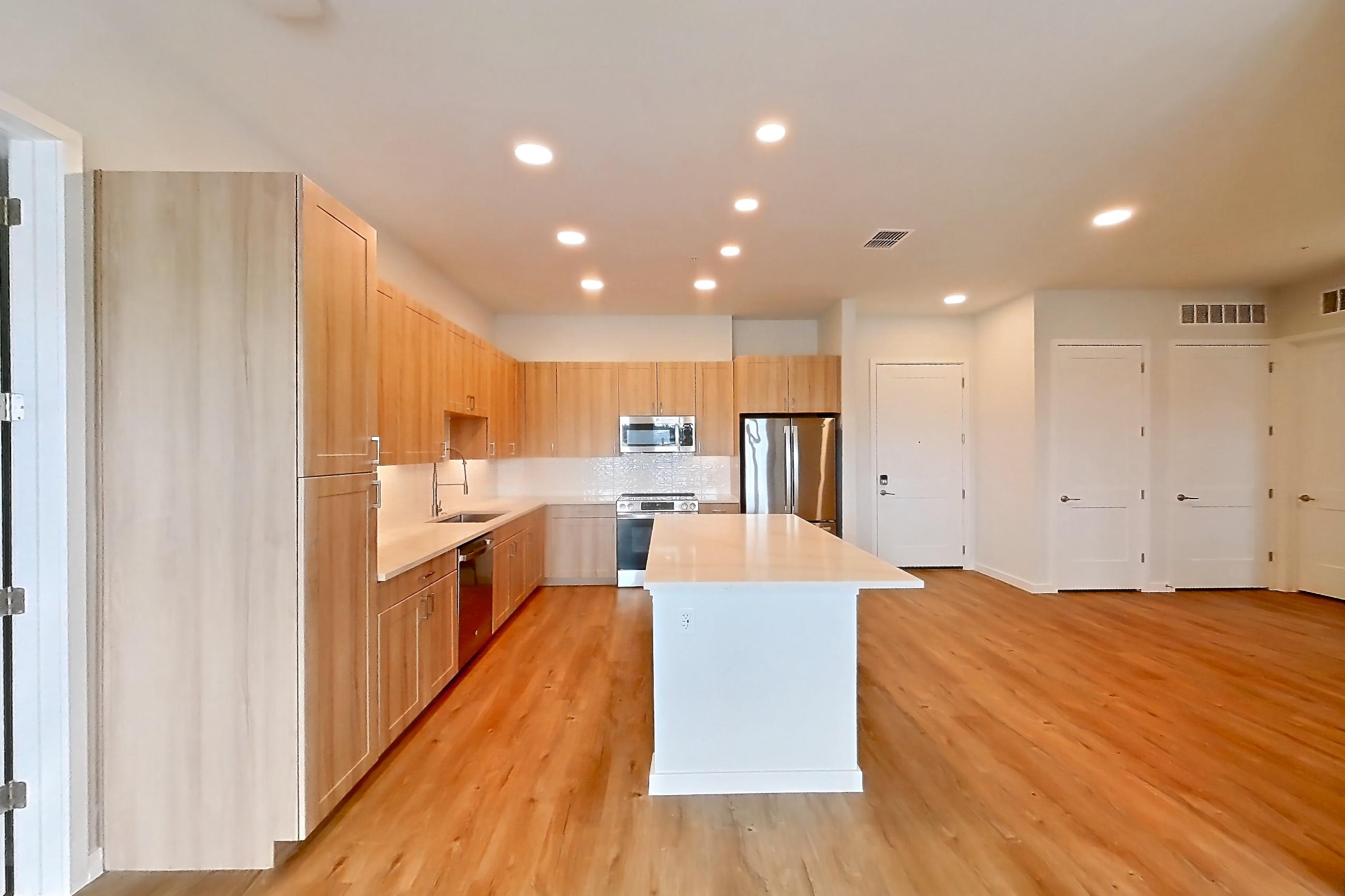 Living space with dishwasher, light countertops, light wood-finish flooring, oven/range, refrigerator, and stainless steel appliances, Apartment 466 at Lantower Bayside
