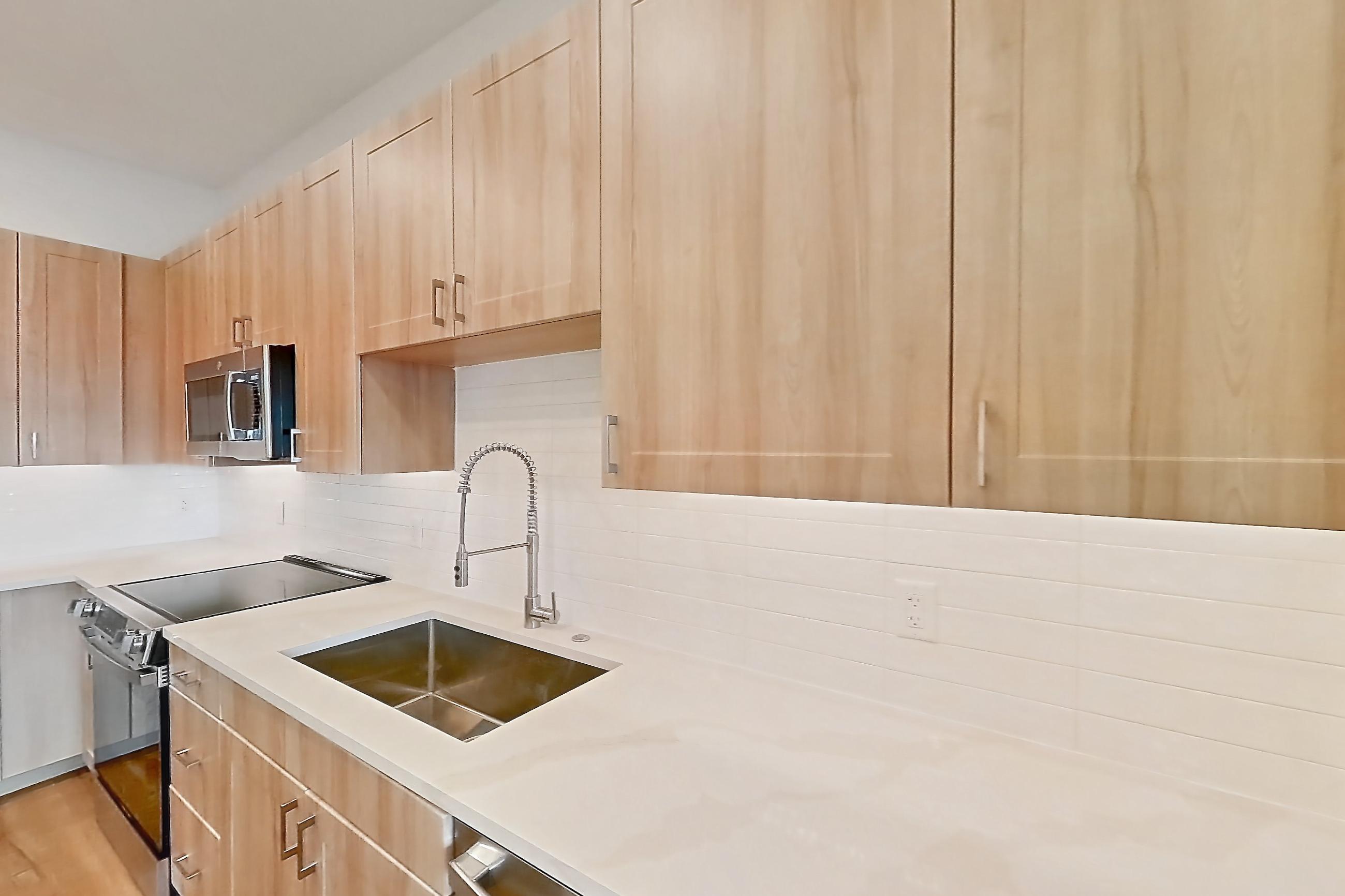 Kitchen with dishwasher, electric range, light countertops, light stone countertops, light wood-finish flooring, oven/range, refrigerator, and stainless steel appliances, Apartment 469 at Lantower Bayside