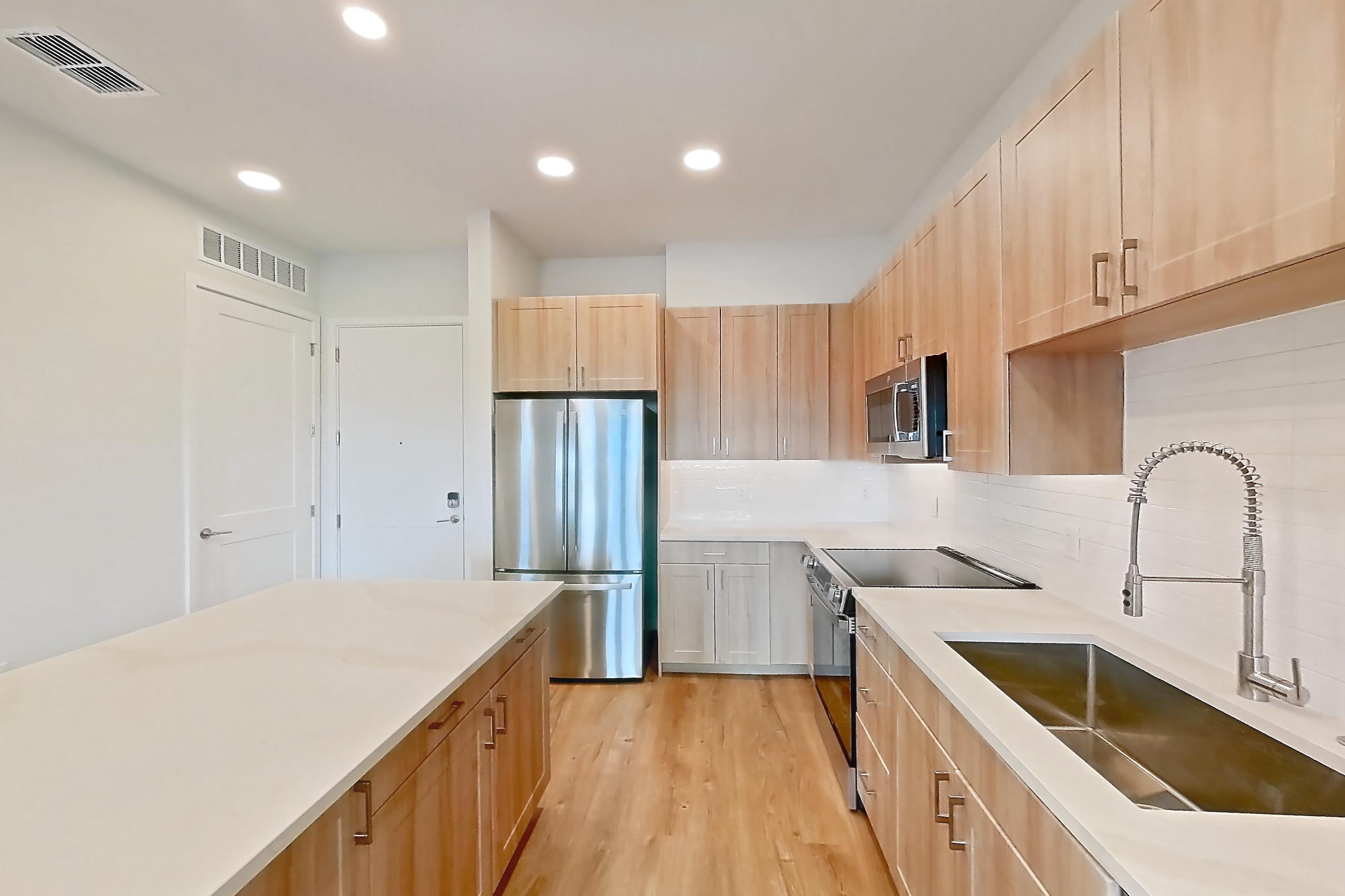 Kitchen with dishwasher, electric range, light countertops, light stone countertops, light wood-finish flooring, oven/range, refrigerator, and stainless steel appliances, Apartment 469 at Lantower Bayside