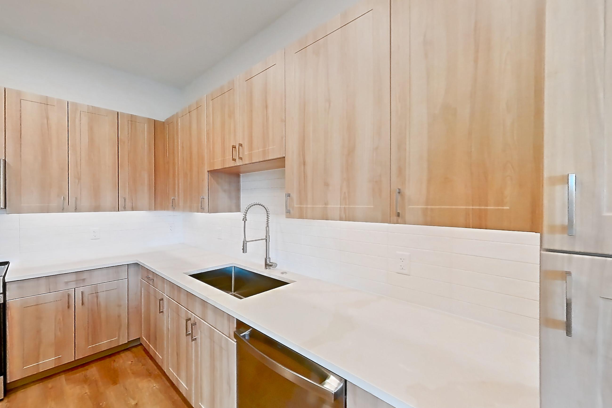 Kitchen with dishwasher, electric range, light countertops, light stone countertops, light wood-finish flooring, microwave, oven/range, refrigerator, and stainless steel appliances, Apartment 474 at Lantower Bayside