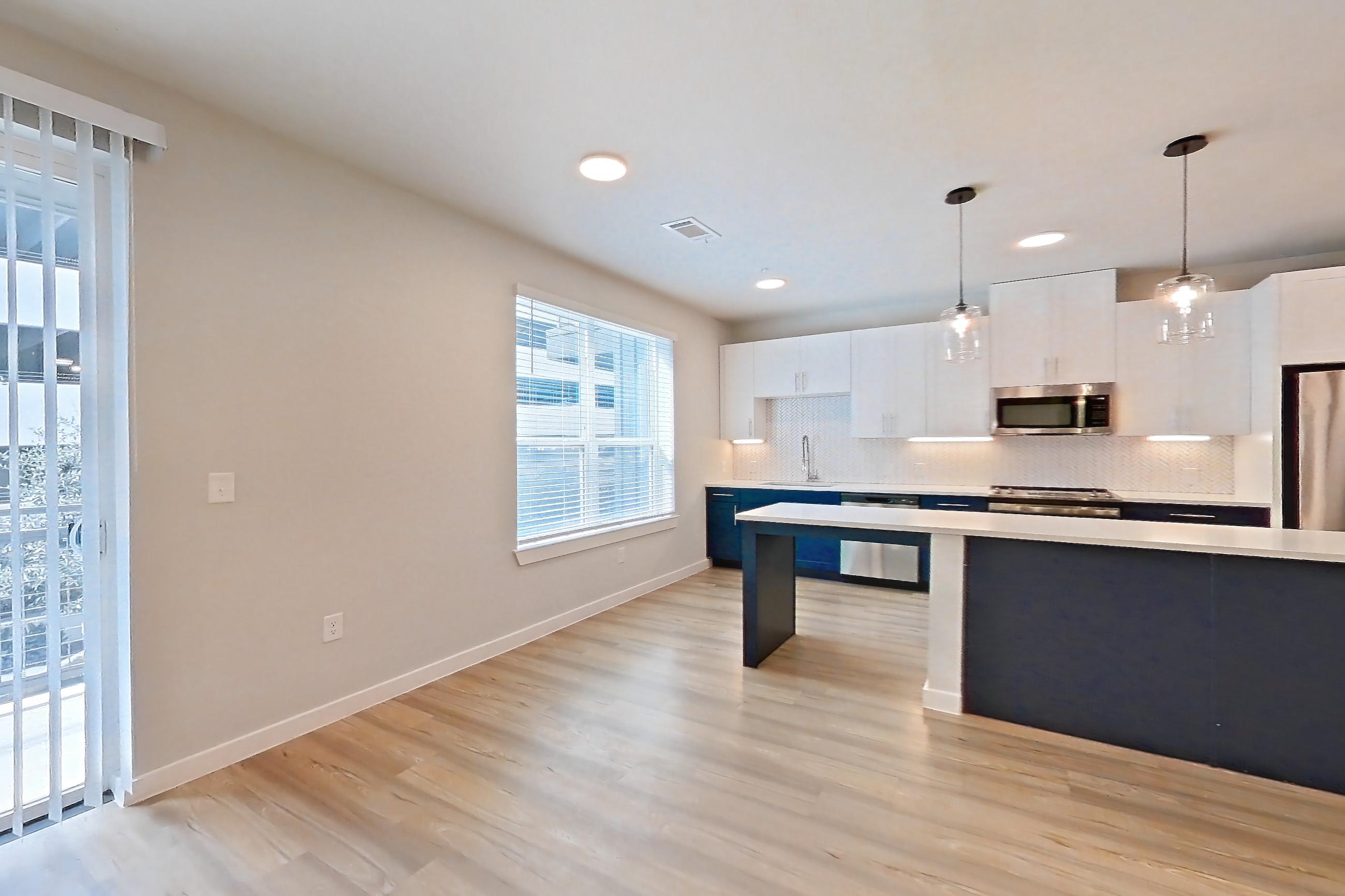 Living space with dishwasher, light countertops, light wood-finish flooring, microwave, refrigerator, and stainless steel appliances, Apartment 2219 at Bridge at The Blockyard