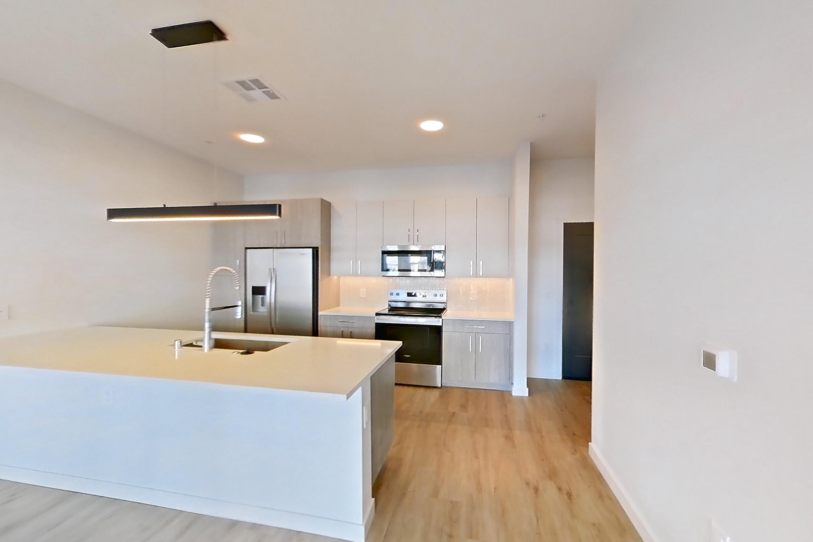 Living room with electric range, light countertops, light wood-finish flooring, oven/range, and stainless steel appliances, Apartment 428 at Gemma