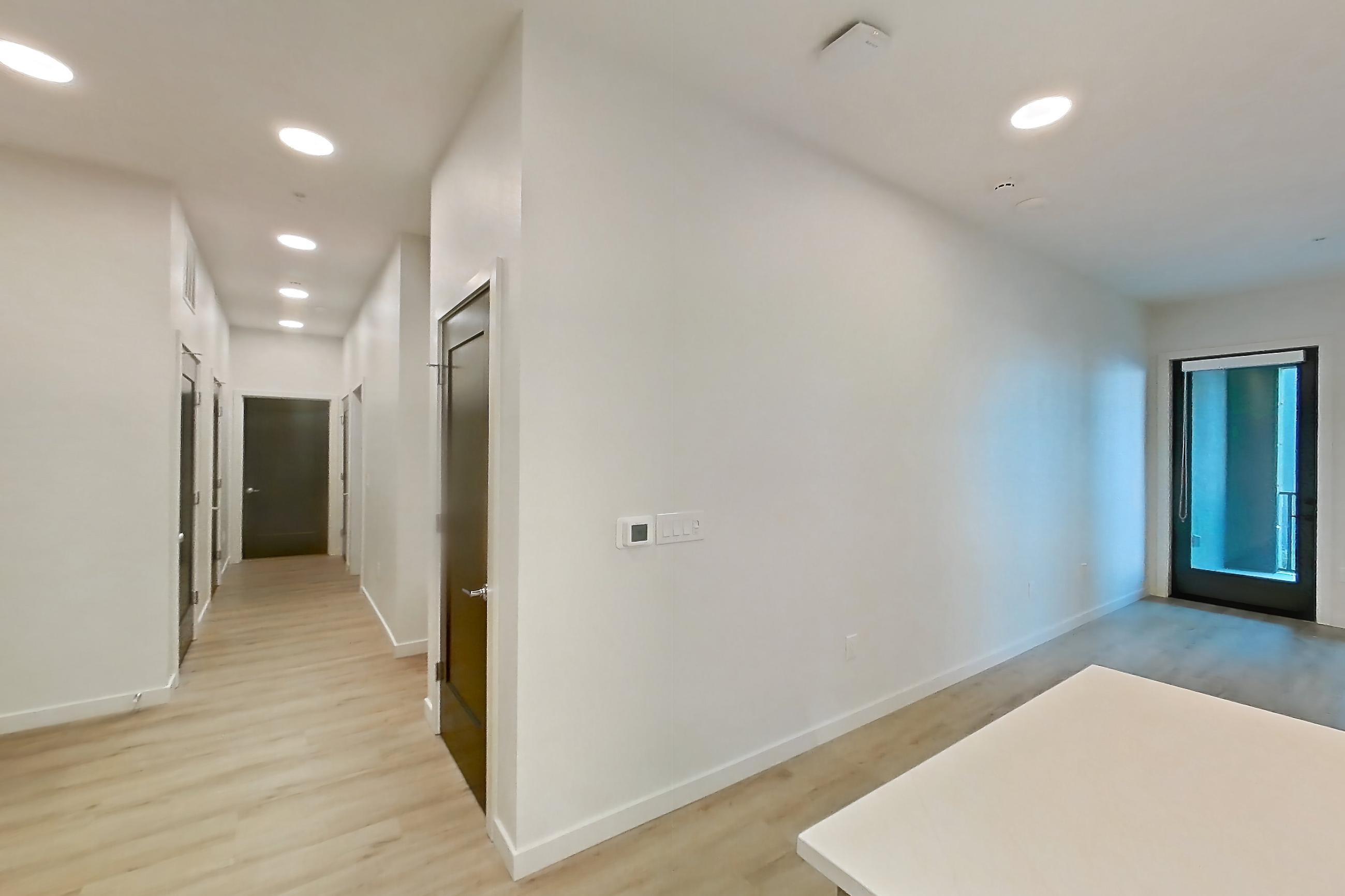 Kitchen with dishwasher, electric range, light countertops, light stone countertops, light wood-finish flooring, microwave, oven/range, refrigerator, stainless steel appliances, water & ice dispenser, and white appliances, Apartment 404 at Gemma