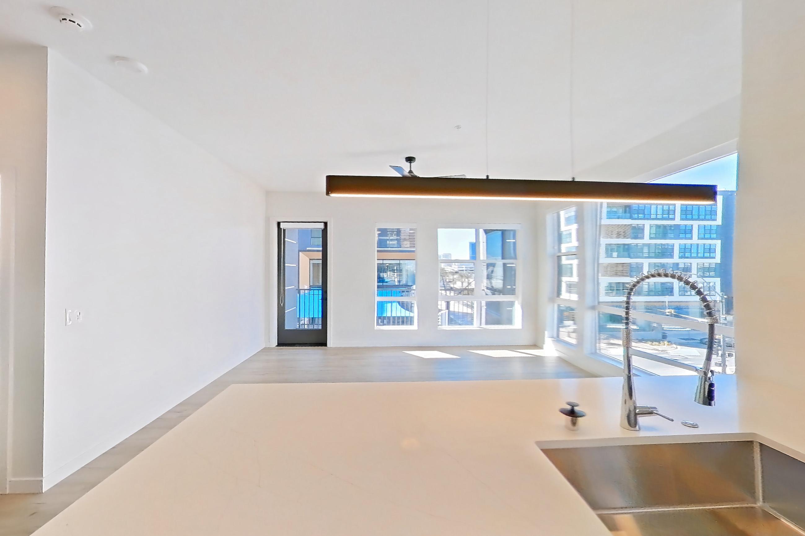 Kitchen with dishwasher, electric range, light countertops, light stone countertops, light wood-finish flooring, microwave, oven/range, refrigerator, stainless steel appliances, water & ice dispenser, and white appliances, Apartment 402 at Gemma