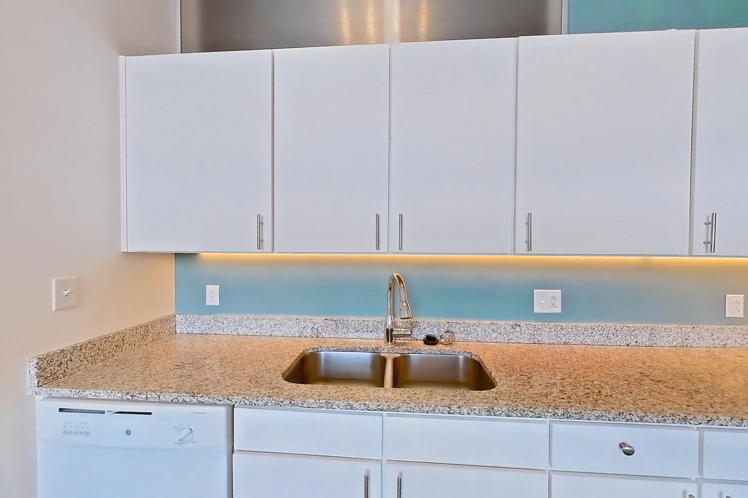 Kitchen with dishwasher, electric range, light concrete flooring, light countertops, light stone countertops, microwave, oven/range, refrigerator, and white appliances, Apartment 1013 at Parcels at Concourse