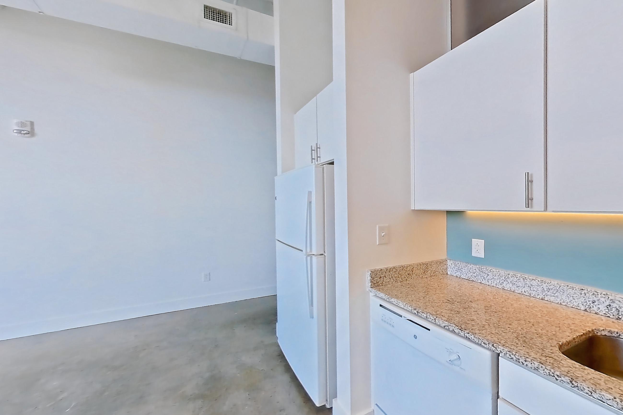 Kitchen with dishwasher, electric range, light concrete flooring, light countertops, light stone countertops, microwave, oven/range, refrigerator, and white appliances, Apartment 1013 at Parcels at Concourse