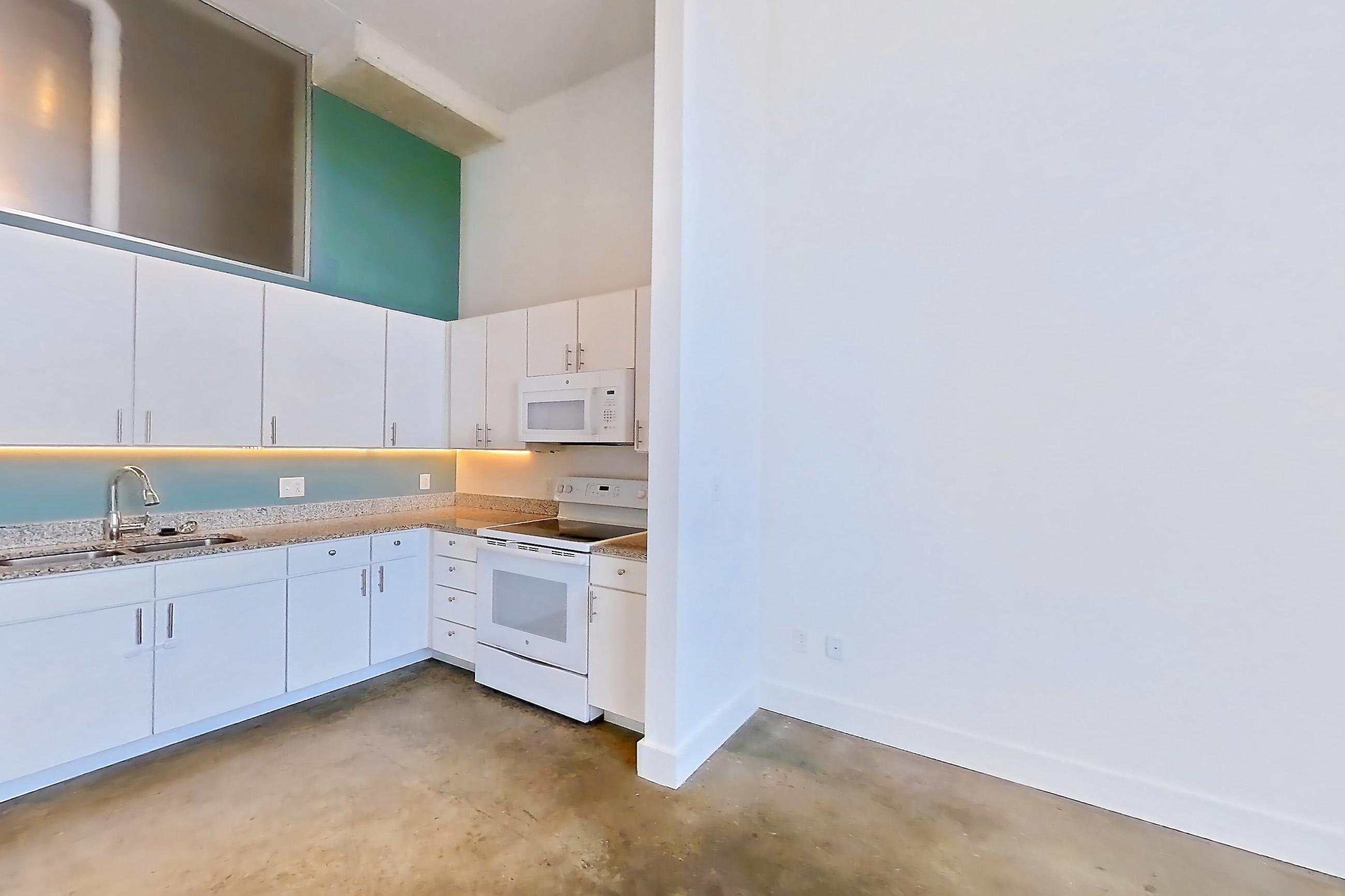 Living space with concrete flooring, dishwasher, electric range, light concrete flooring, light countertops, light stone countertops, oven/range, refrigerator, and white appliances, Apartment 1013 at Parcels at Concourse