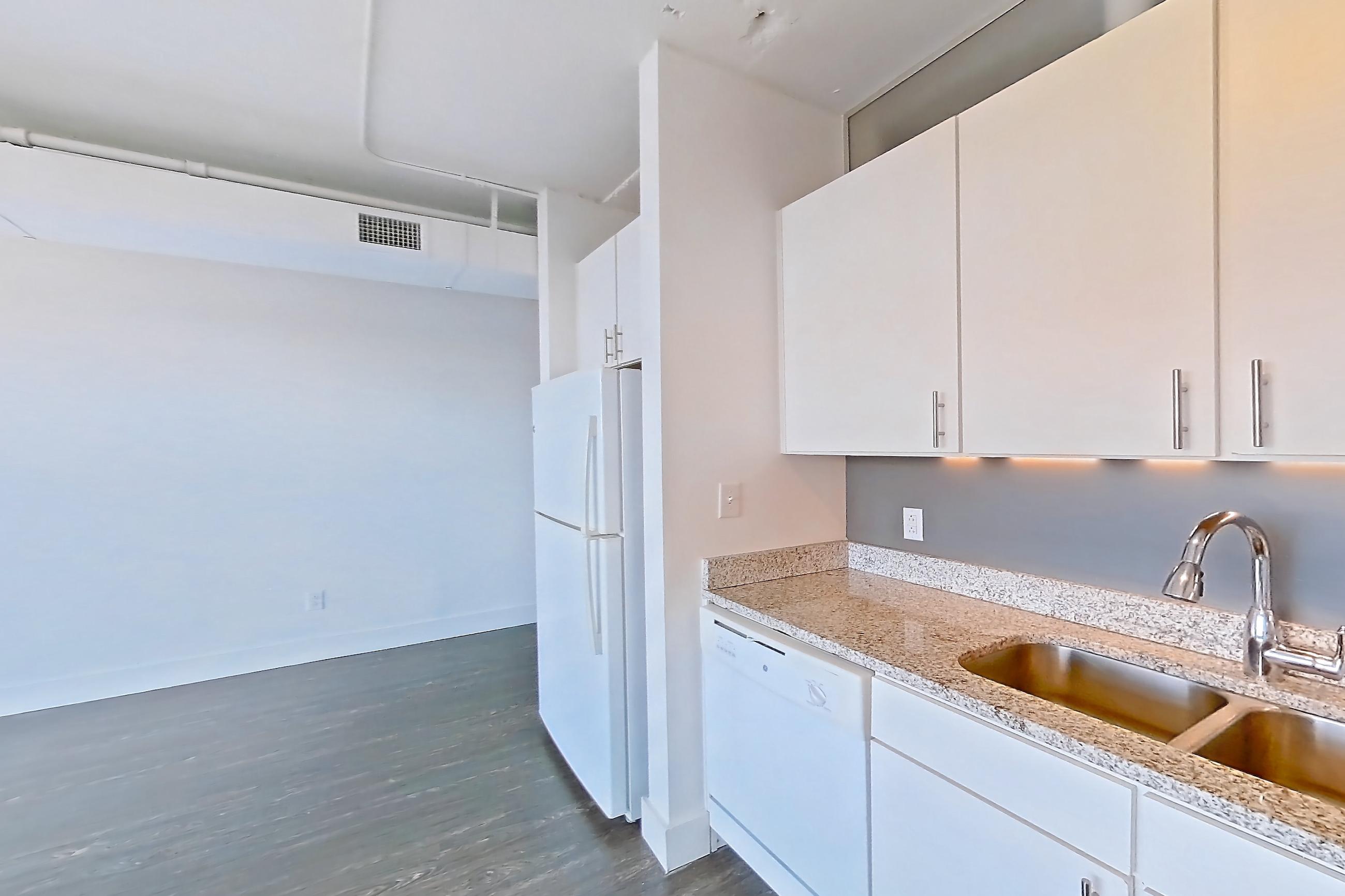 Kitchen with dark wood-finish flooring, dishwasher, electric range, light countertops, light stone countertops, microwave, oven/range, refrigerator, and white appliances, Apartment 729 at Parcels at Concourse