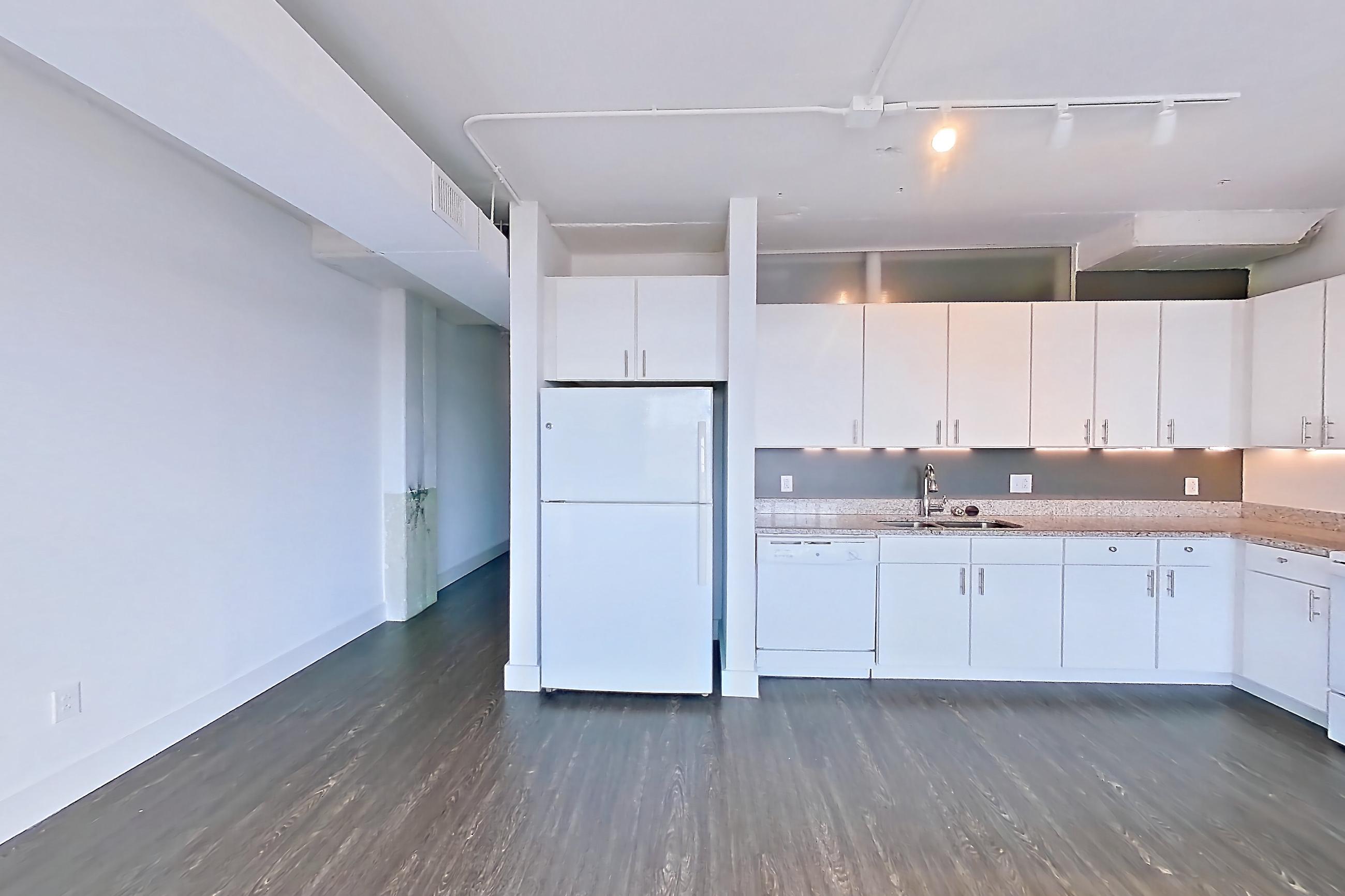 Living space with dark wood-finish flooring, dishwasher, electric range, light stone countertops, oven/range, refrigerator, and white appliances, Apartment 729 at Parcels at Concourse