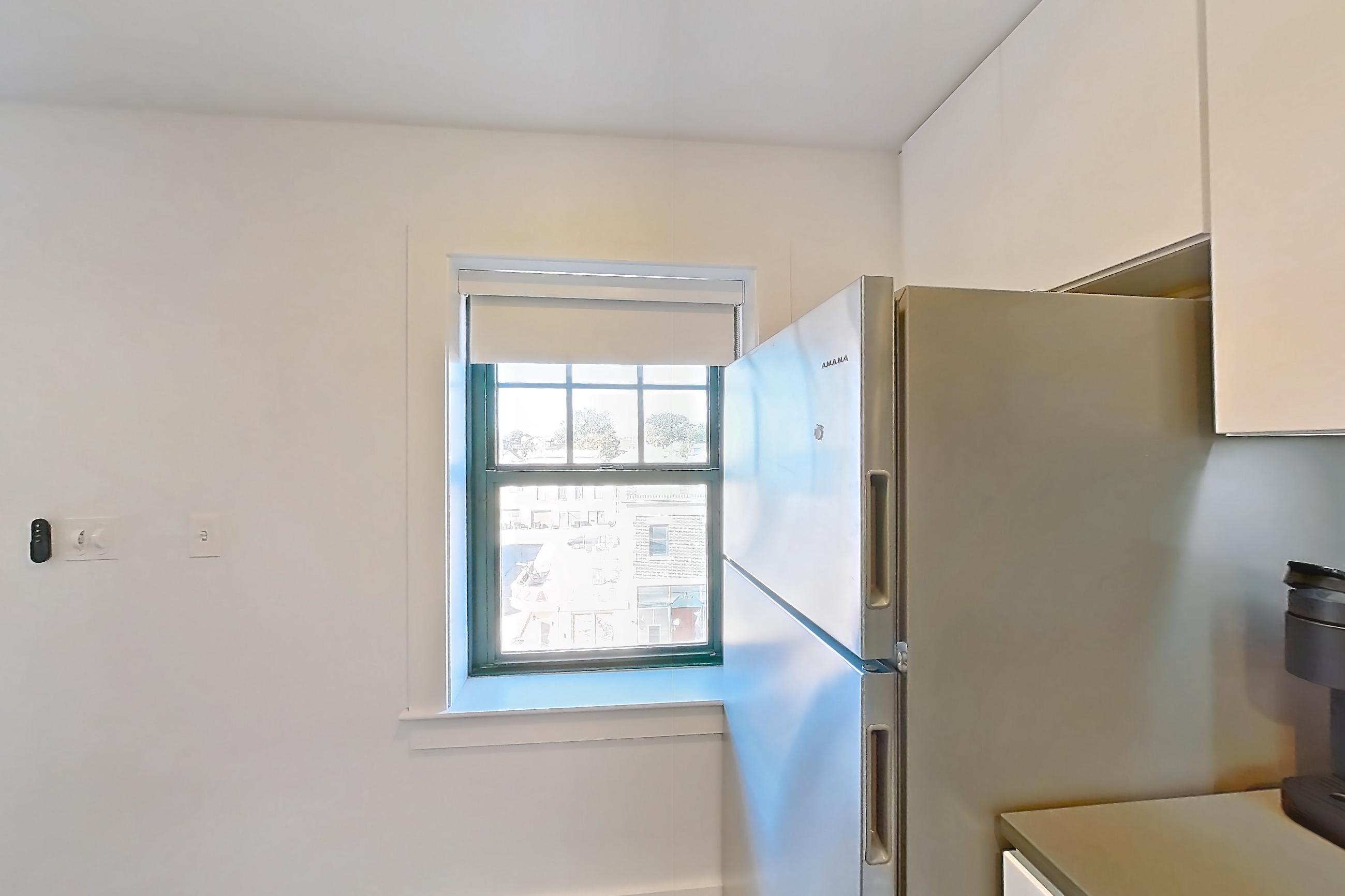 Kitchen with black appliances, cooktop, dishwasher, electric cooktop, light countertops, light wood-finish flooring, and stainless steel appliances, Apartment 1-415 at Netherland and Monarch