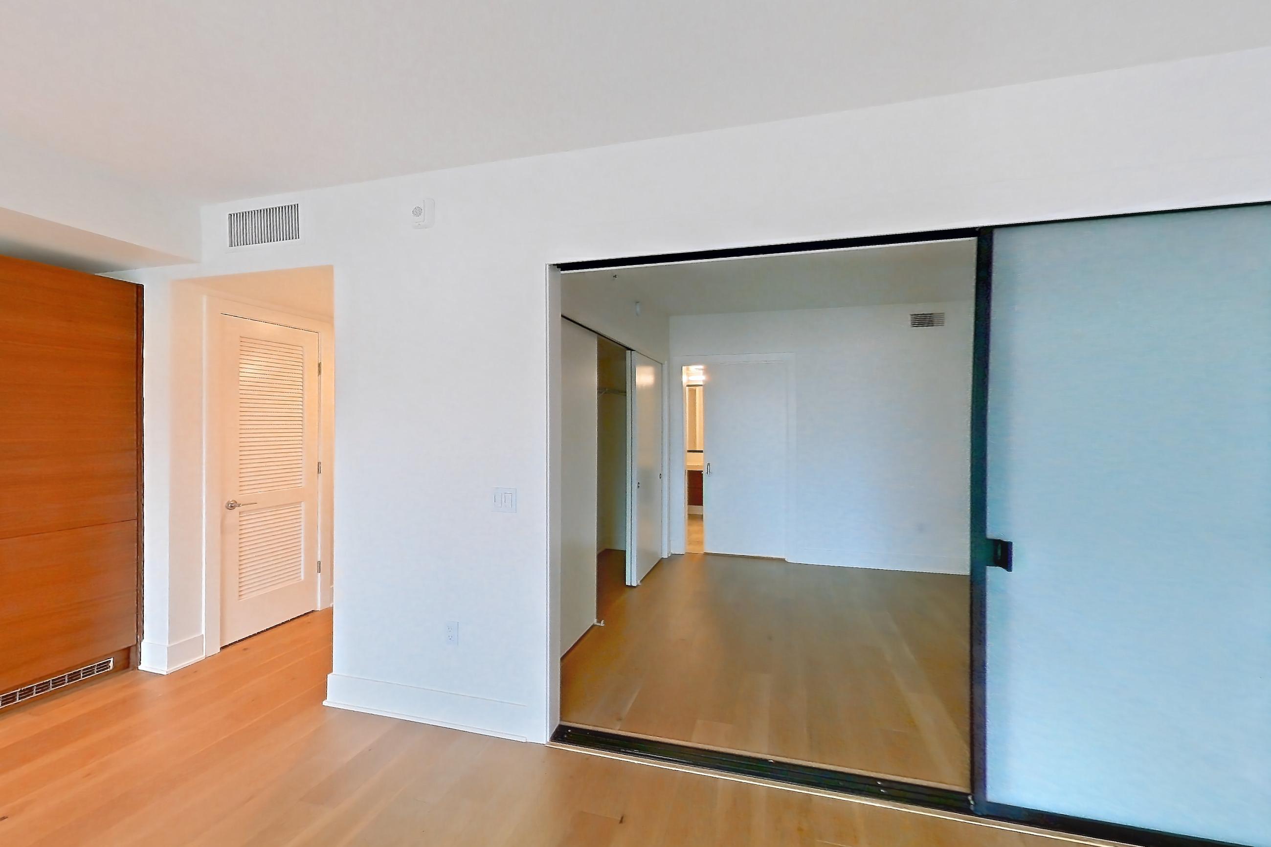 Living room with cooktop, gas cooktop, light countertops, light wood-finish flooring, oven/range, stainless steel appliances, and wood-finish flooring, Apartment 605 at Konrad on the Park