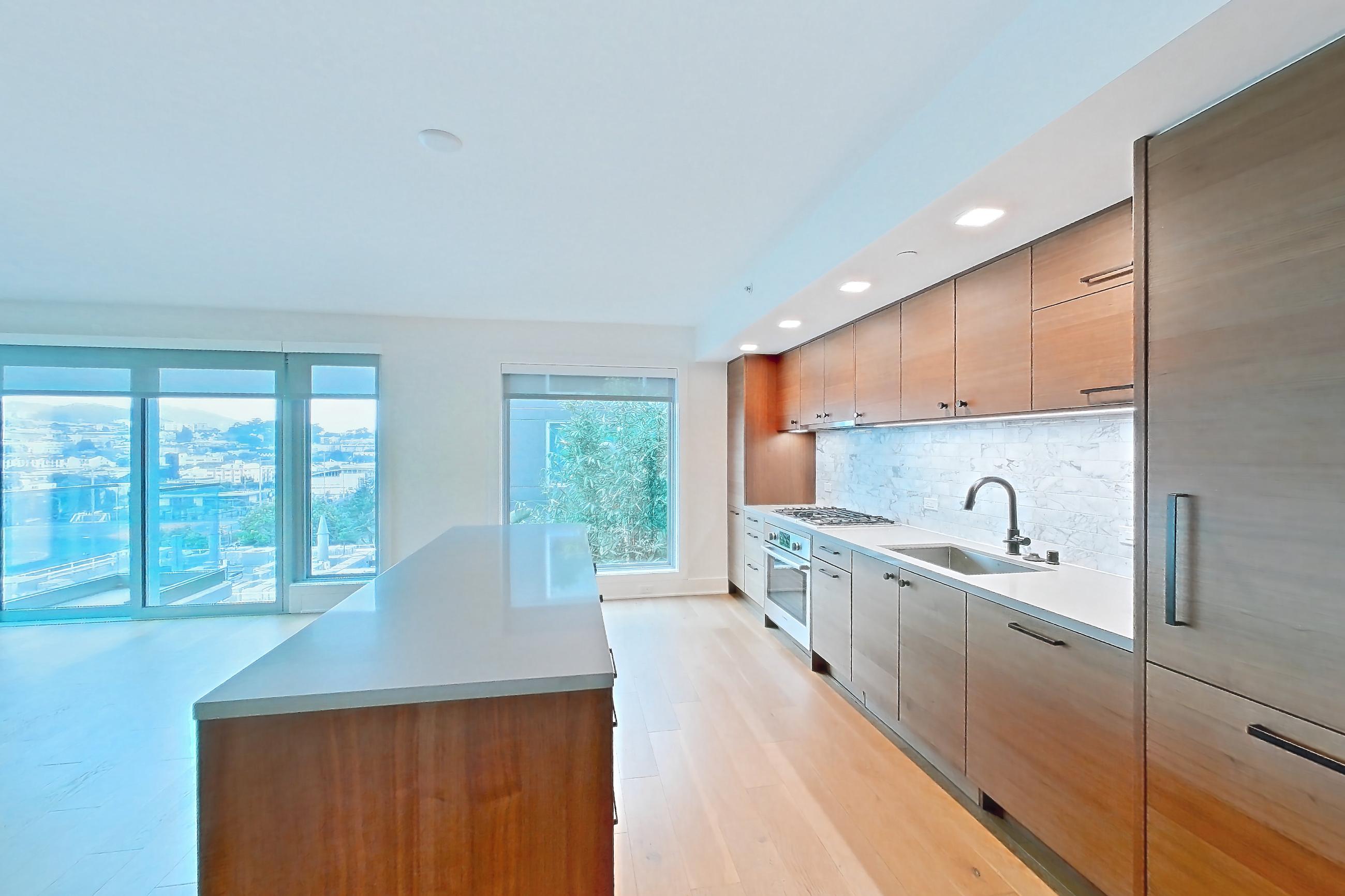 Kitchen entry with cooktop, gas cooktop, light countertops, light wood-finish flooring, oven/range, stainless steel appliances, and wood-finish flooring, Apartment 418 at Konrad on the Park