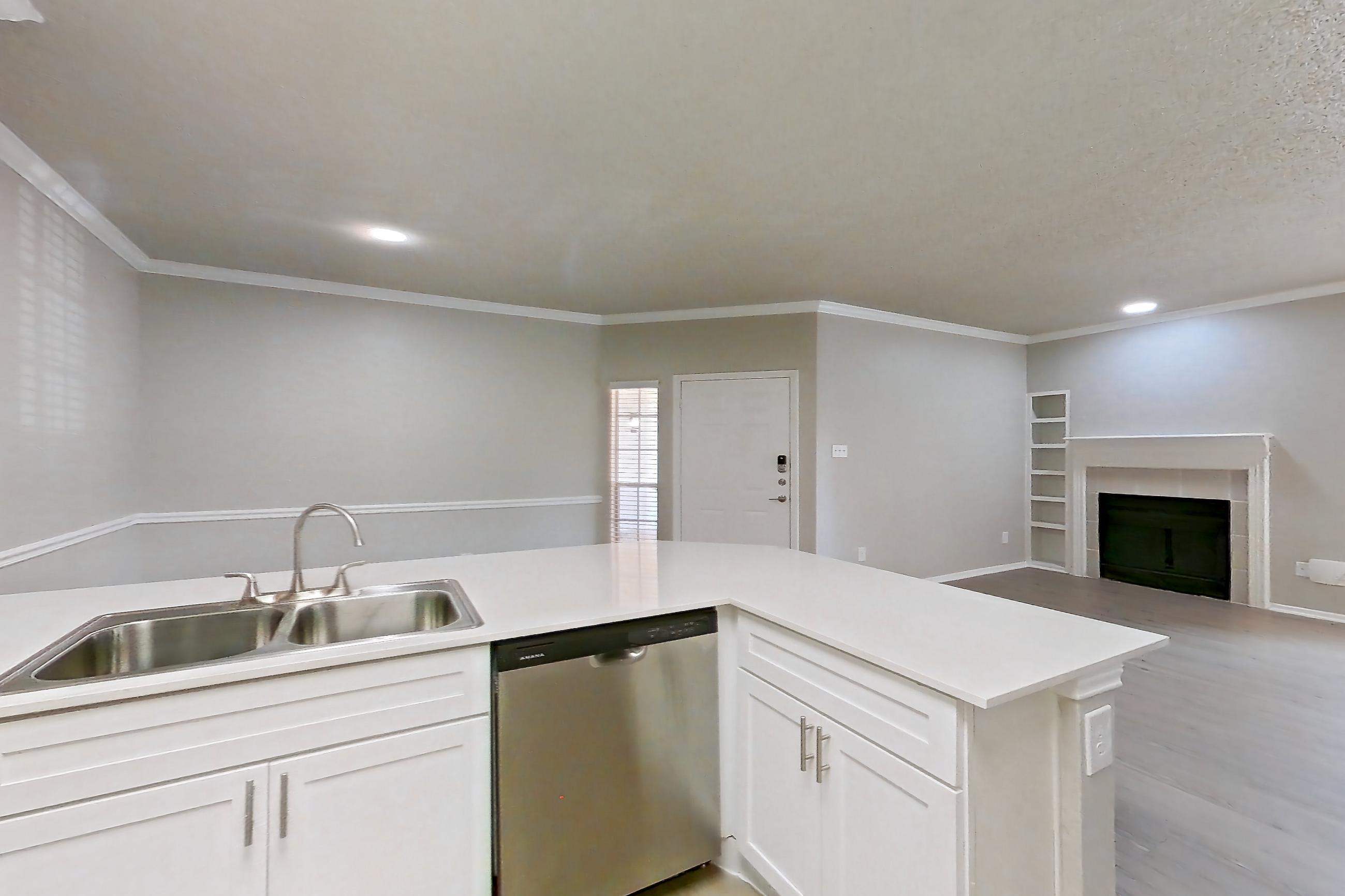 Kitchen with dishwasher, electric range, fireplace, light countertops, light wood-finish flooring, oven/range, range hood, refrigerator, and stainless steel appliances, Apartment 228 at Museo and Channings Mark