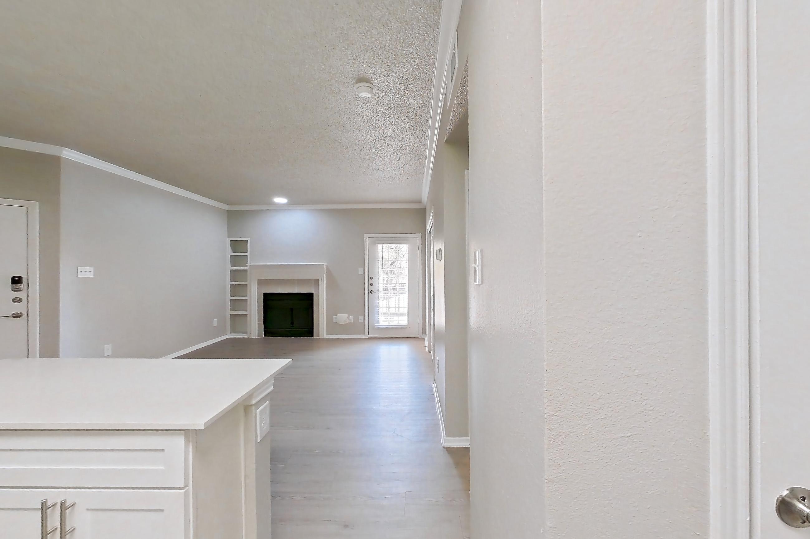 Kitchen with dishwasher, electric range, fireplace, light countertops, light wood-finish flooring, oven/range, range hood, refrigerator, and stainless steel appliances, Apartment 228 at Museo and Channings Mark