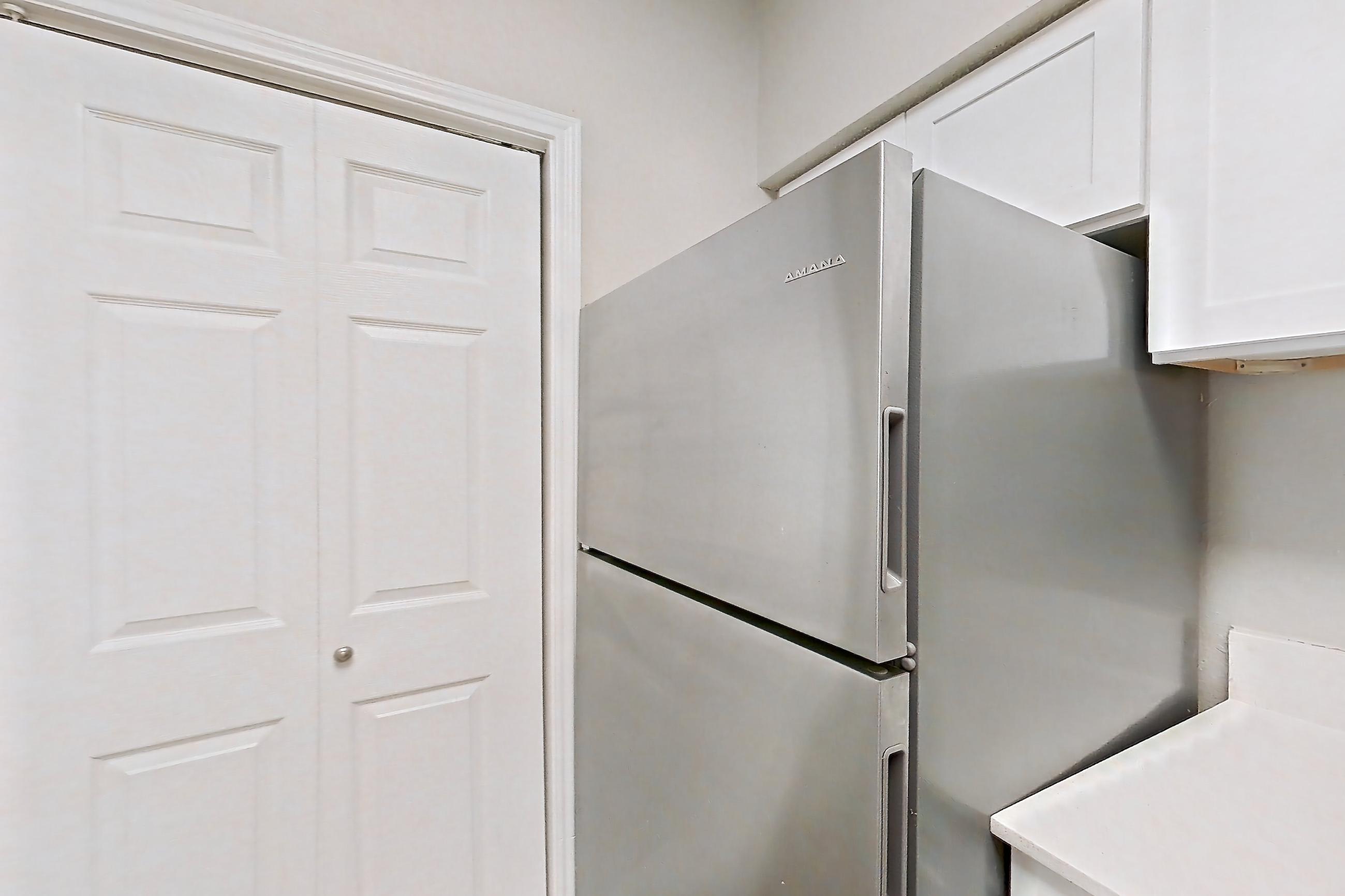 Kitchen with dishwasher, electric range, fireplace, light countertops, light wood-finish flooring, oven/range, range hood, refrigerator, and stainless steel appliances, Apartment 228 at Museo and Channings Mark