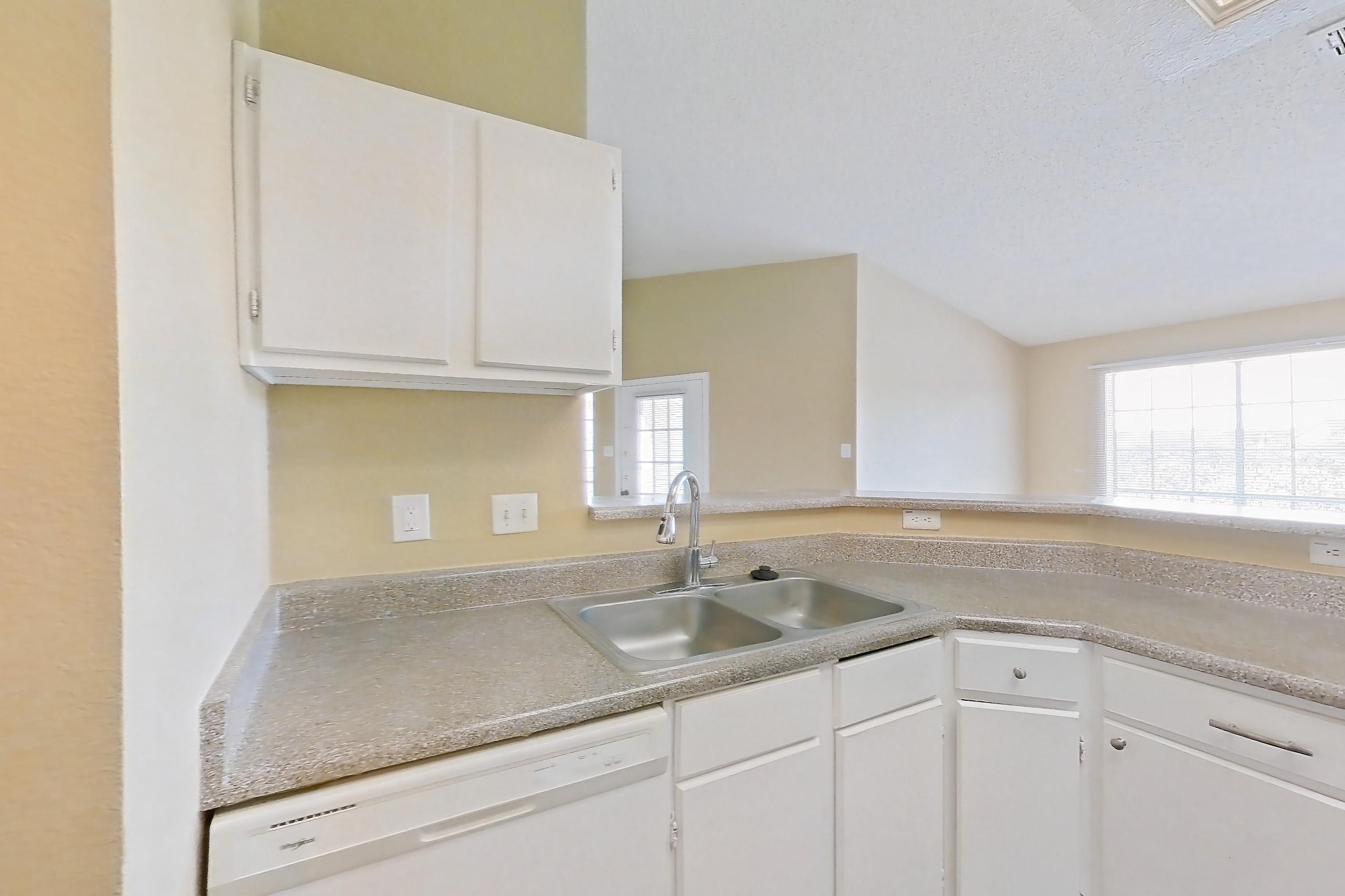 Kitchen with black appliances, dark wood-finish flooring, dishwasher, electric range, in-unit laundry, light countertops, oven/range, range hood, refrigerator, and white appliances, Apartment 921 at Museo and Channings Mark