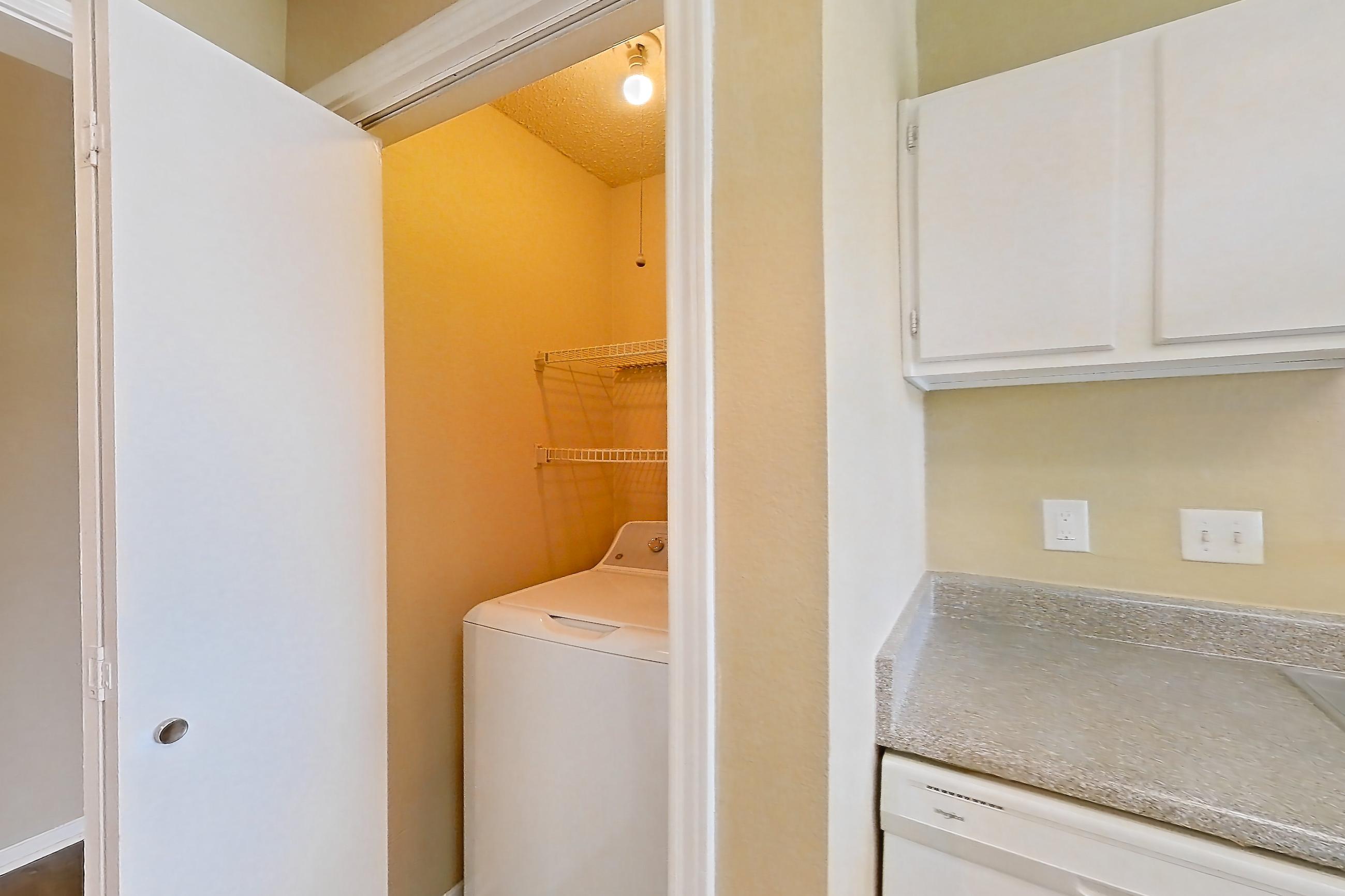 Kitchen with black appliances, dark wood-finish flooring, dishwasher, electric range, in-unit laundry, light countertops, oven/range, range hood, refrigerator, and white appliances, Apartment 921 at Museo and Channings Mark