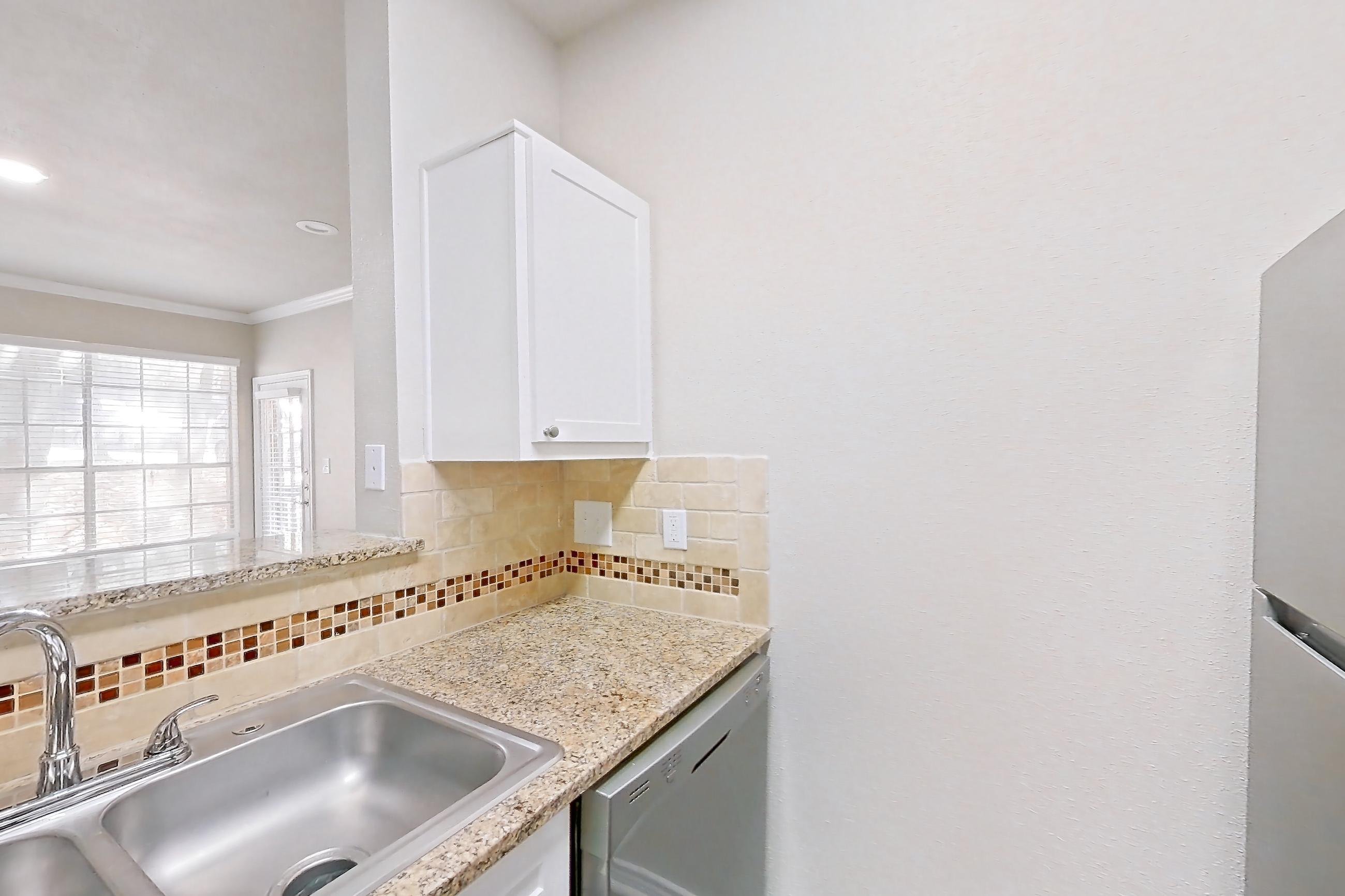 Kitchen with dark wood-finish flooring, dishwasher, electric range, light stone countertops, oven/range, refrigerator, and stainless steel appliances, Apartment 0512 at Museo and Channings Mark