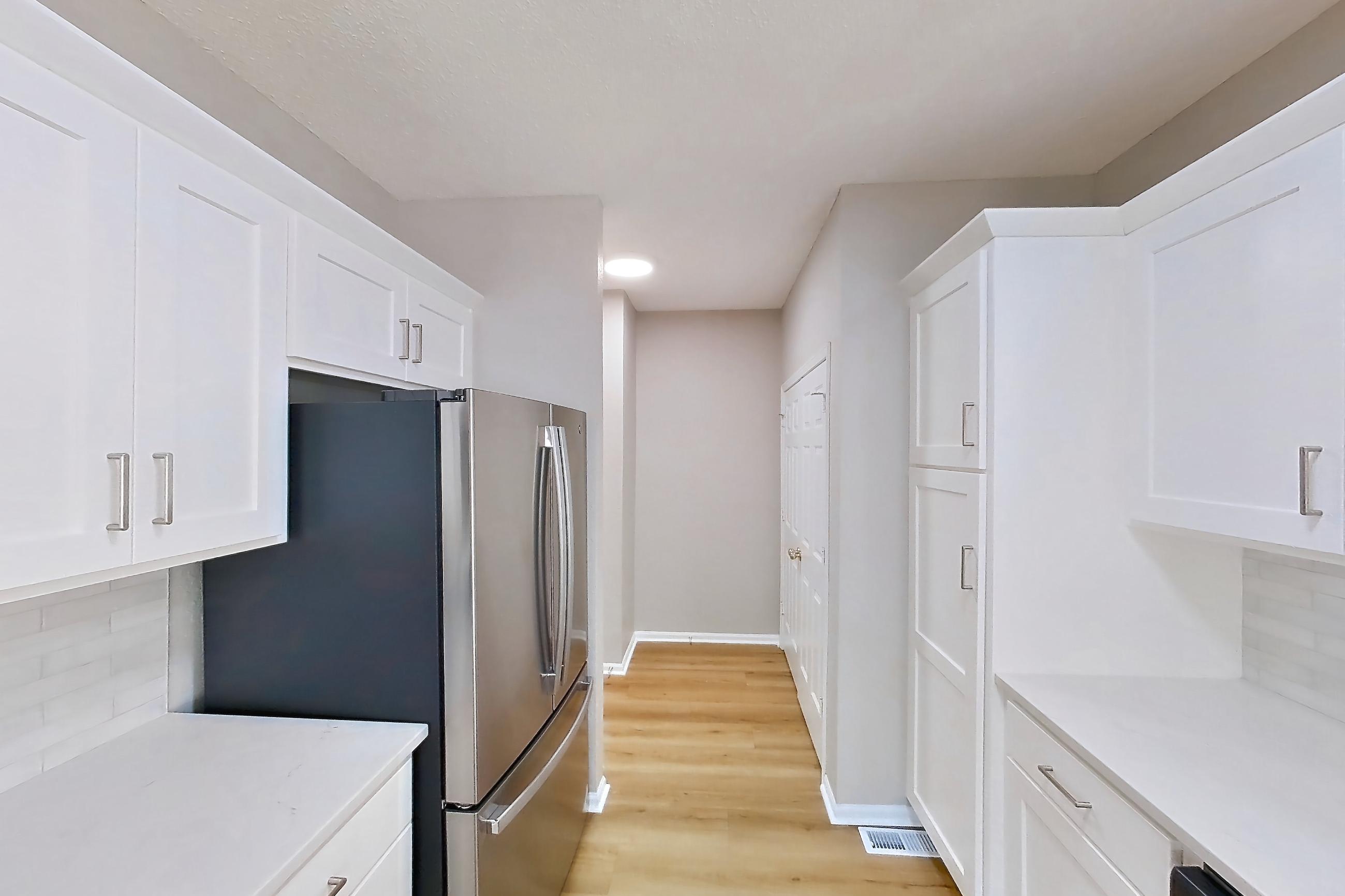 Kitchen with dishwasher, electric range, light countertops, light stone countertops, light wood-finish flooring, microwave, oven/range, refrigerator, and stainless steel appliances, Apartment Walkout Townhome at Bradford Pointe