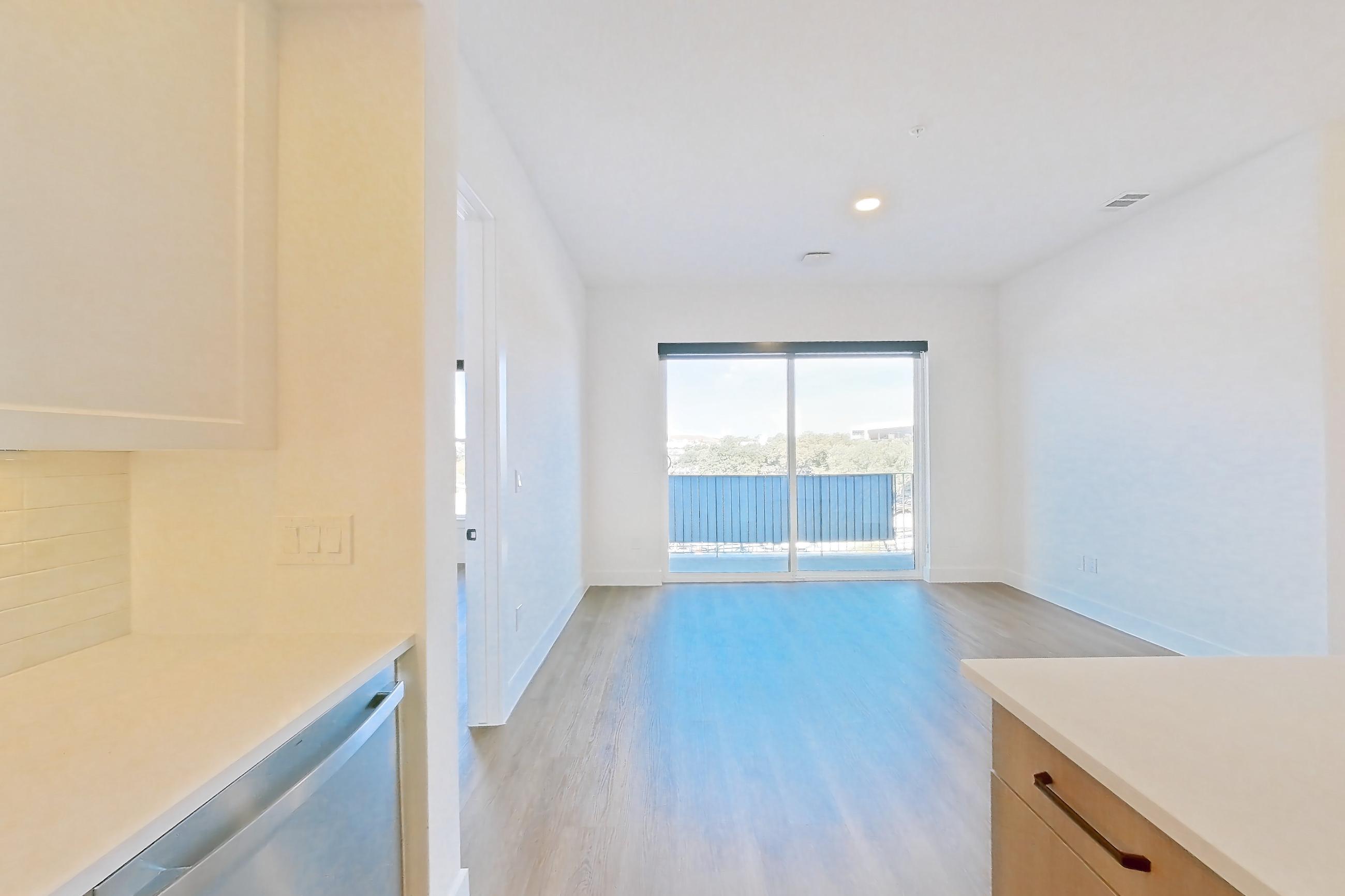 Kitchen with black appliances, dishwasher, electric range, light stone countertops, light wood-finish flooring, oven/range, and stainless steel appliances, Apartment 308 at The Watson