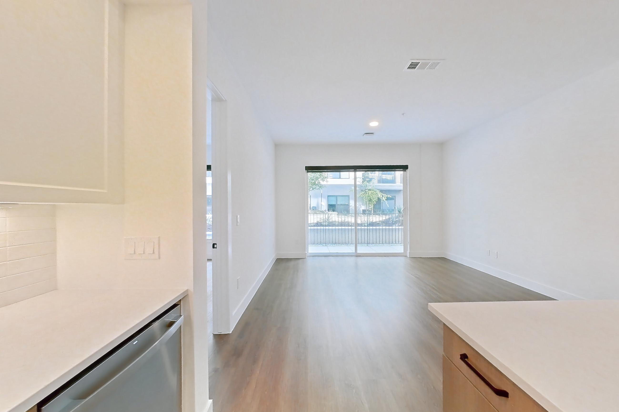Kitchen with dishwasher, light stone countertops, light wood-finish flooring, and stainless steel appliances, Apartment 309 at The Watson