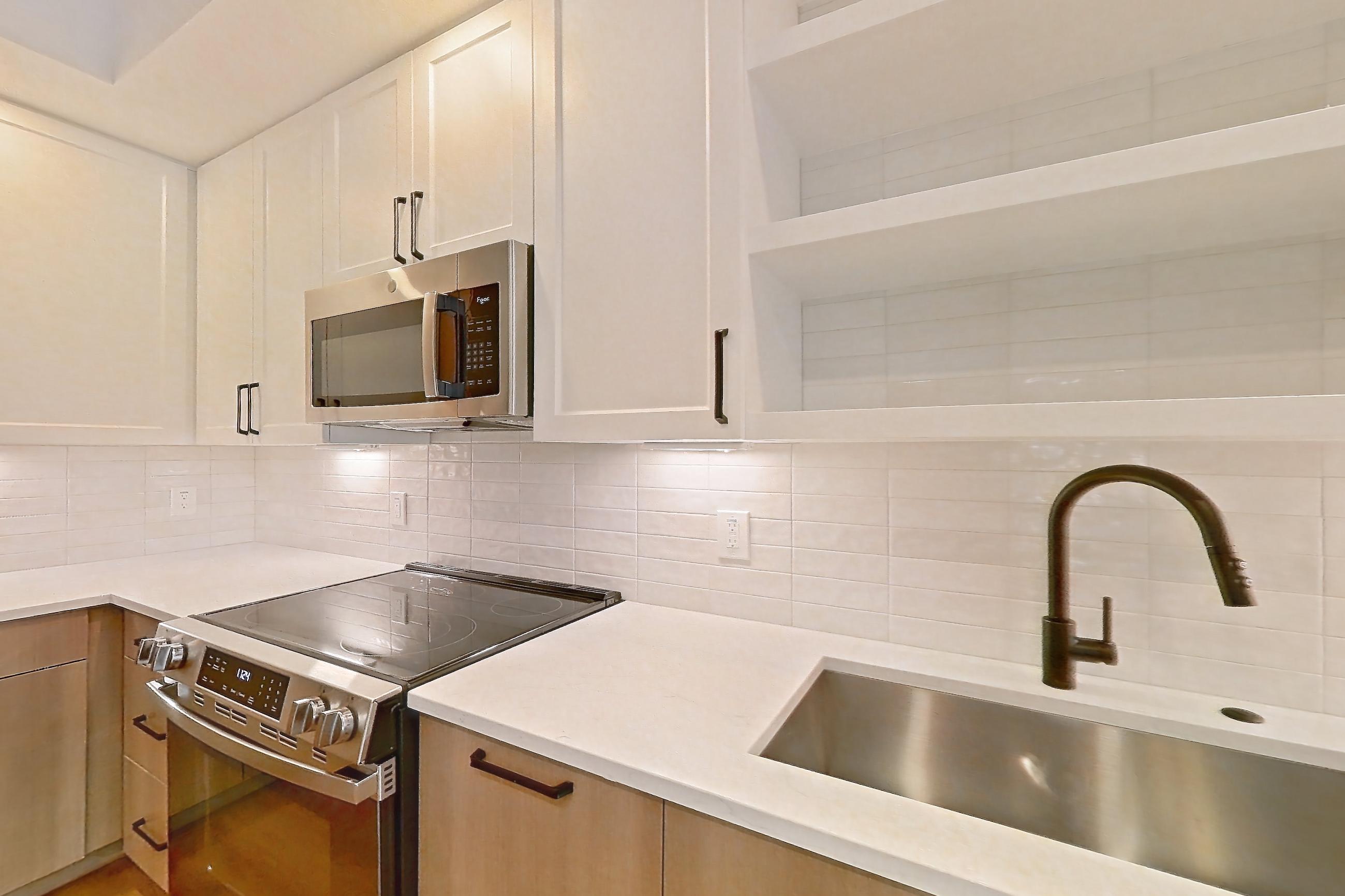 Kitchen with dishwasher, light stone countertops, light wood-finish flooring, and stainless steel appliances, Apartment 309 at The Watson