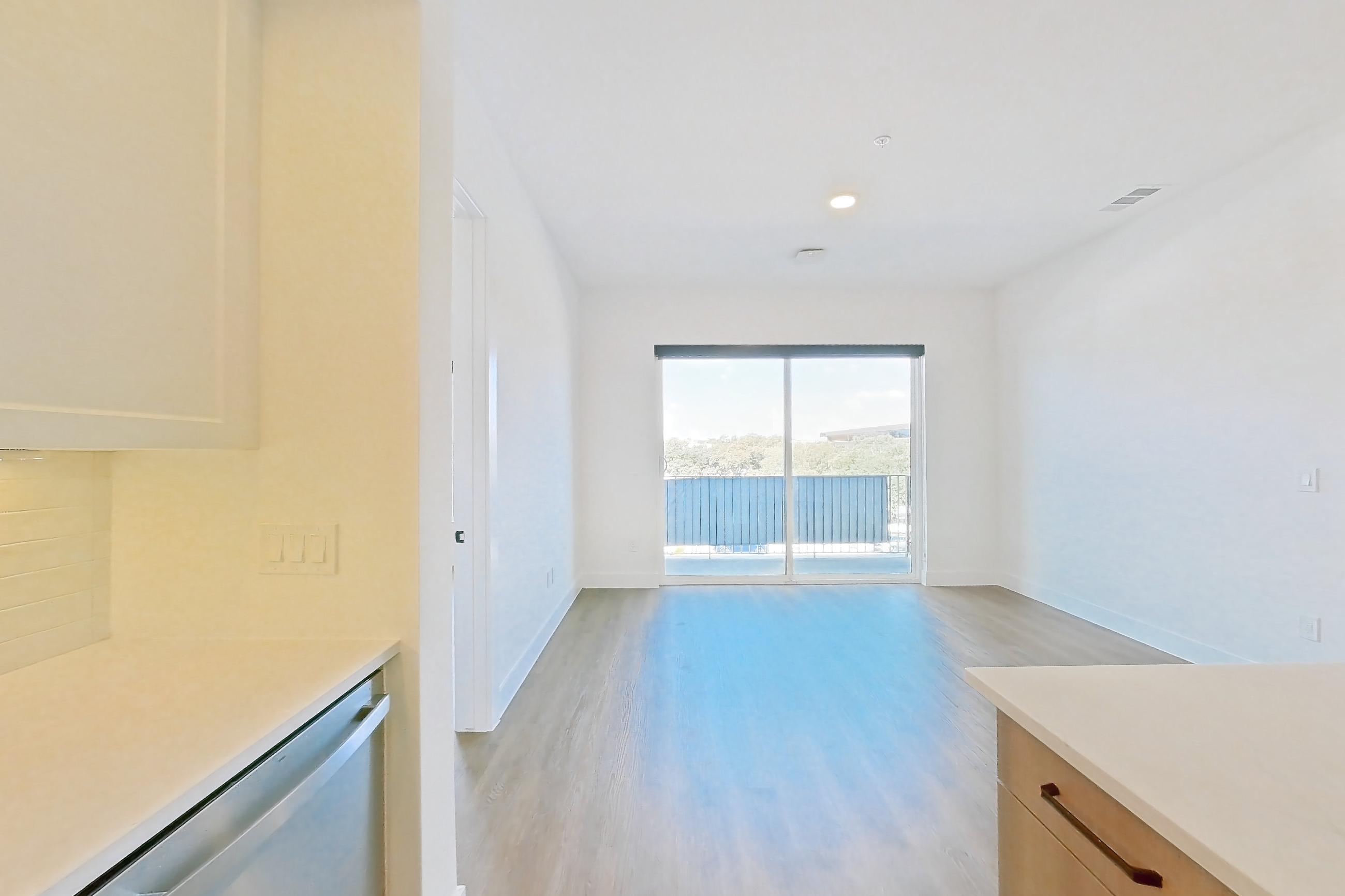 Kitchen with dishwasher, electric range, light stone countertops, light wood-finish flooring, and stainless steel appliances, Apartment 310 at The Watson