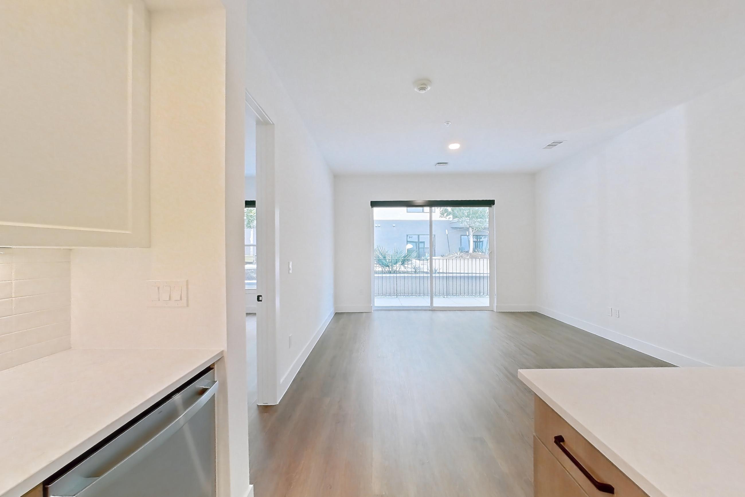 Kitchen with black appliances, dishwasher, electric range, light countertops, light stone countertops, light wood-finish flooring, oven/range, and stainless steel appliances, Apartment 311 at The Watson