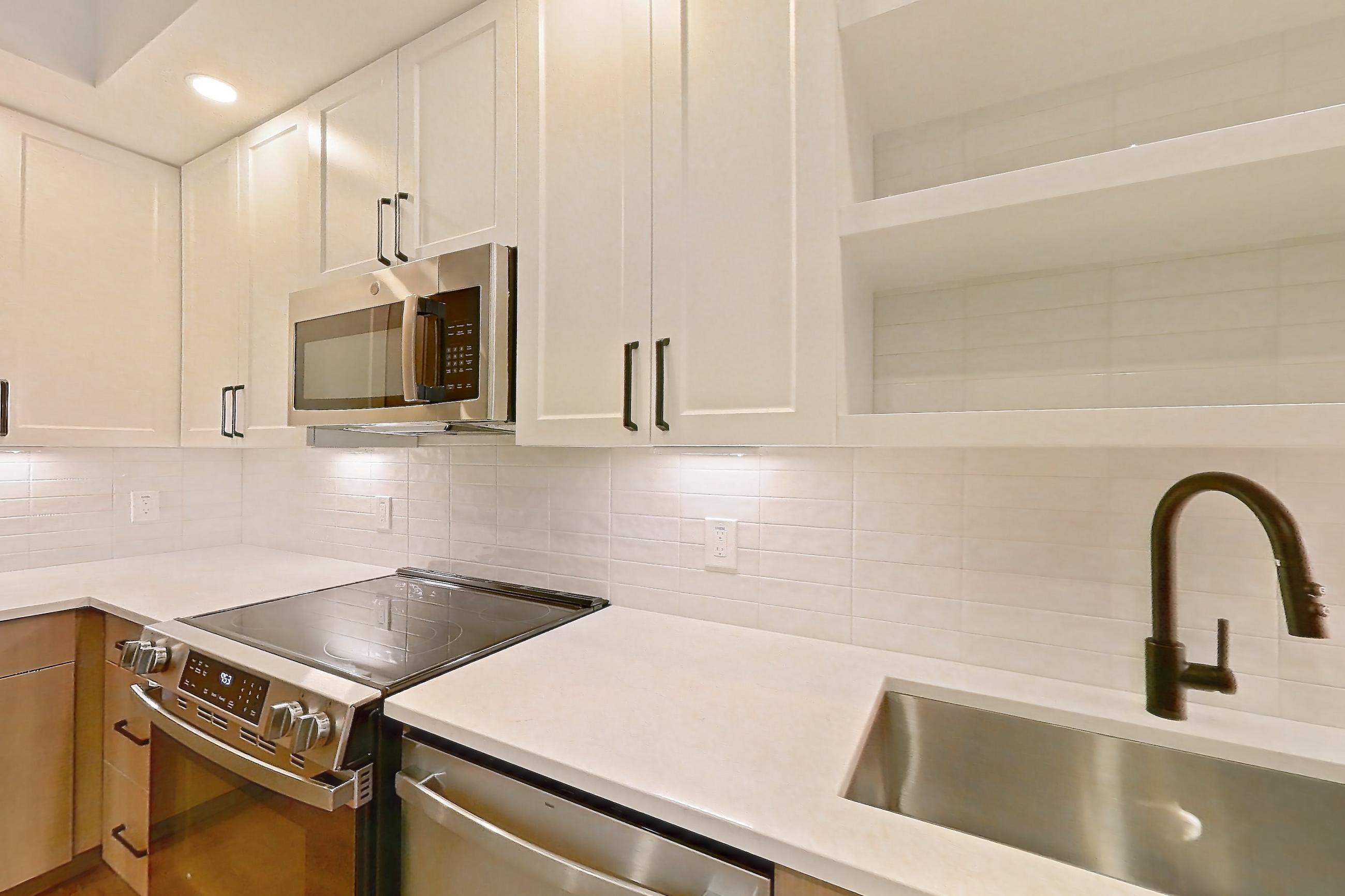 Kitchen with dishwasher, light stone countertops, light wood-finish flooring, and stainless steel appliances, Apartment 313 at The Watson
