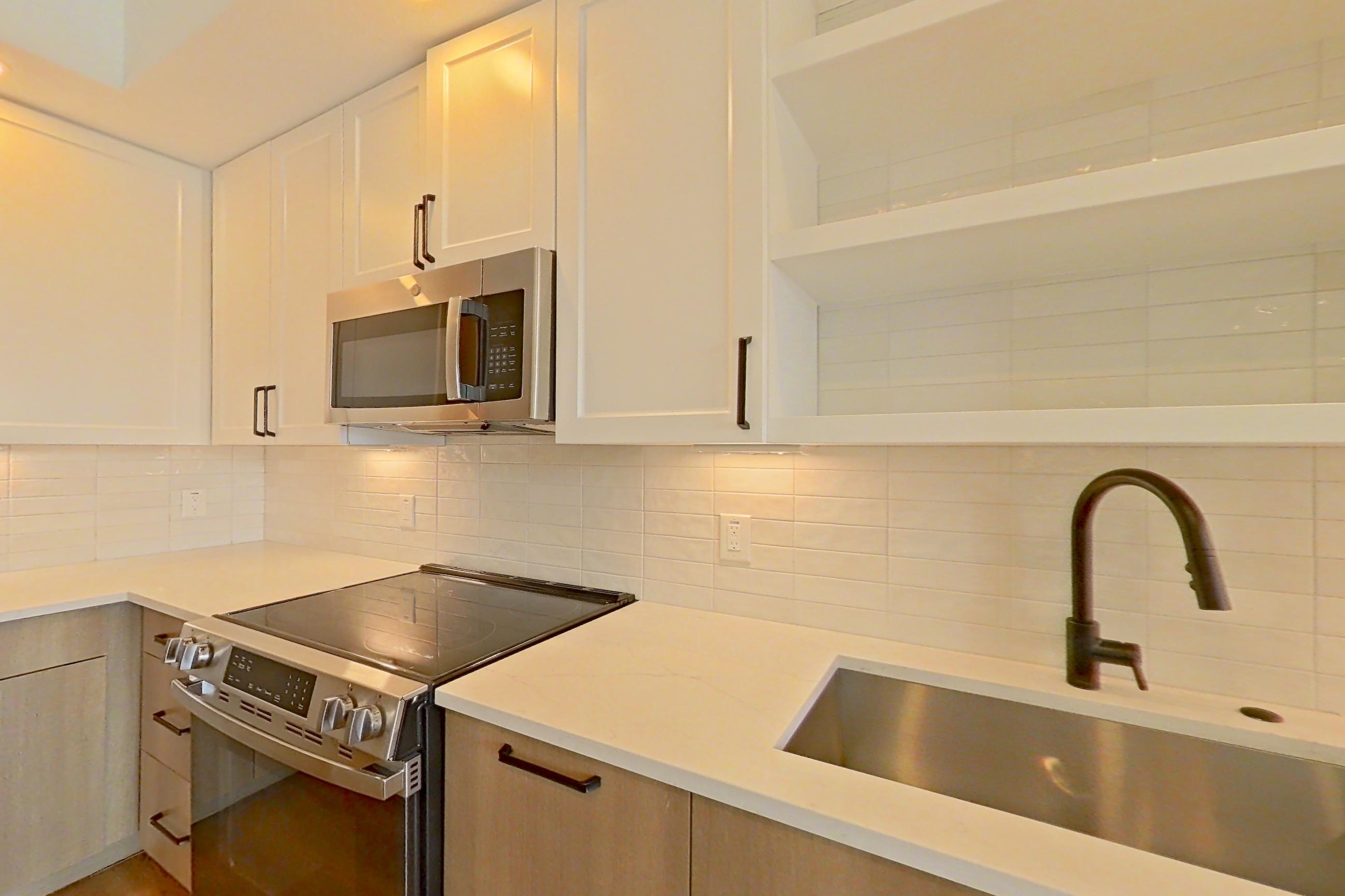 Kitchen with dishwasher, electric range, light stone countertops, light wood-finish flooring, and stainless steel appliances, Apartment 314 at The Watson