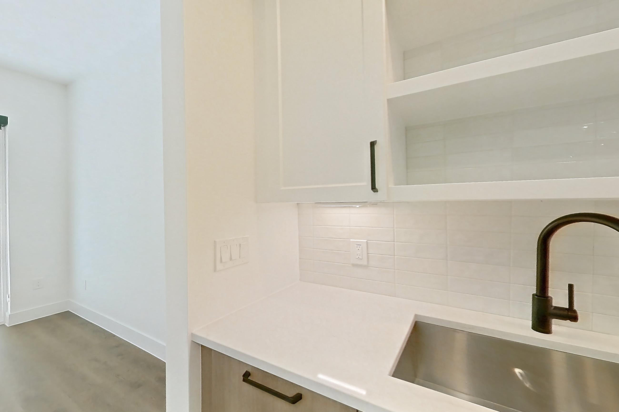 Kitchen with light stone countertops and light wood-finish flooring, Apartment 315 at The Watson