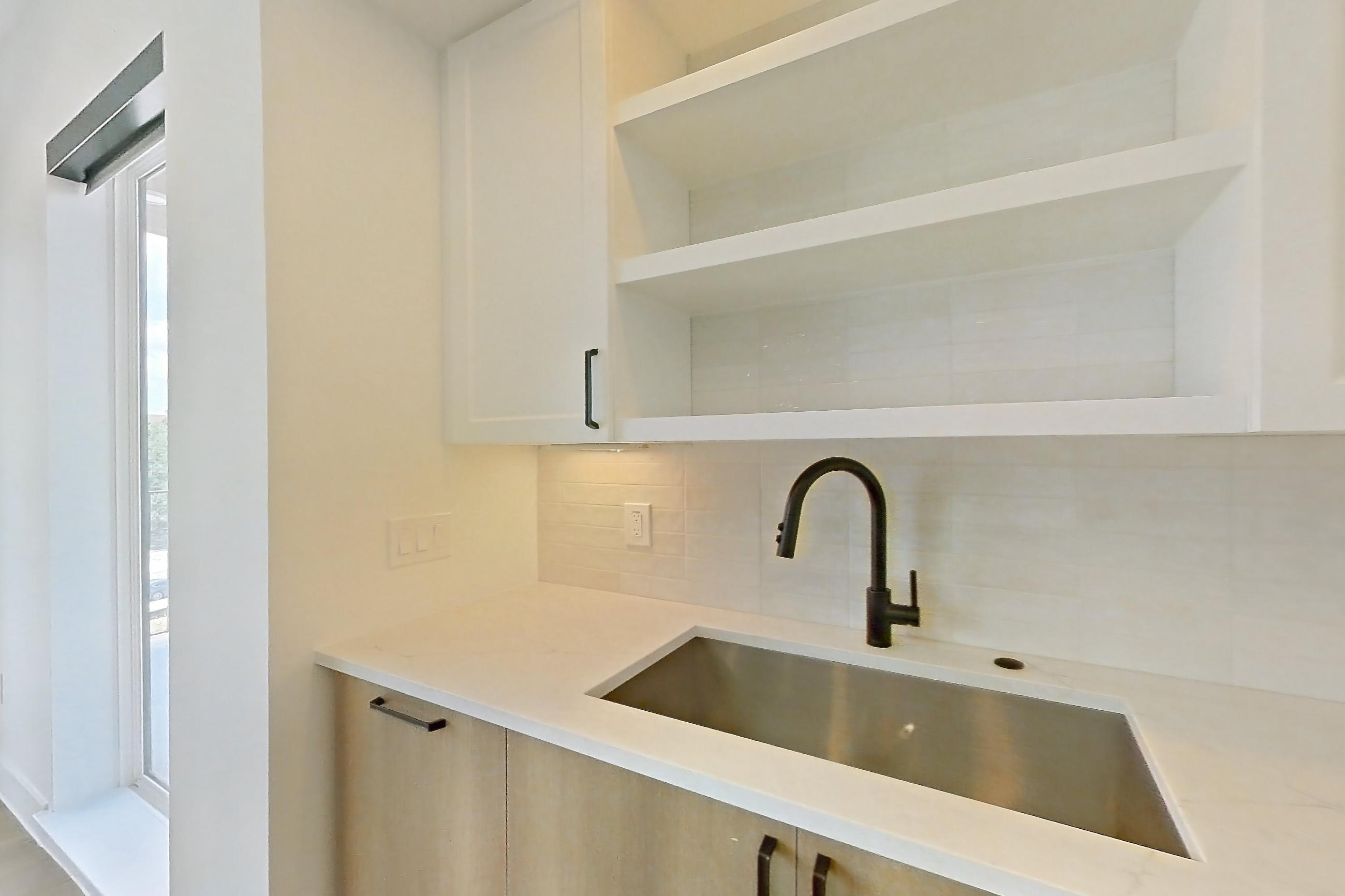 Kitchen with dishwasher, light stone countertops, light wood-finish flooring, refrigerator, and stainless steel appliances, Apartment 316 at The Watson