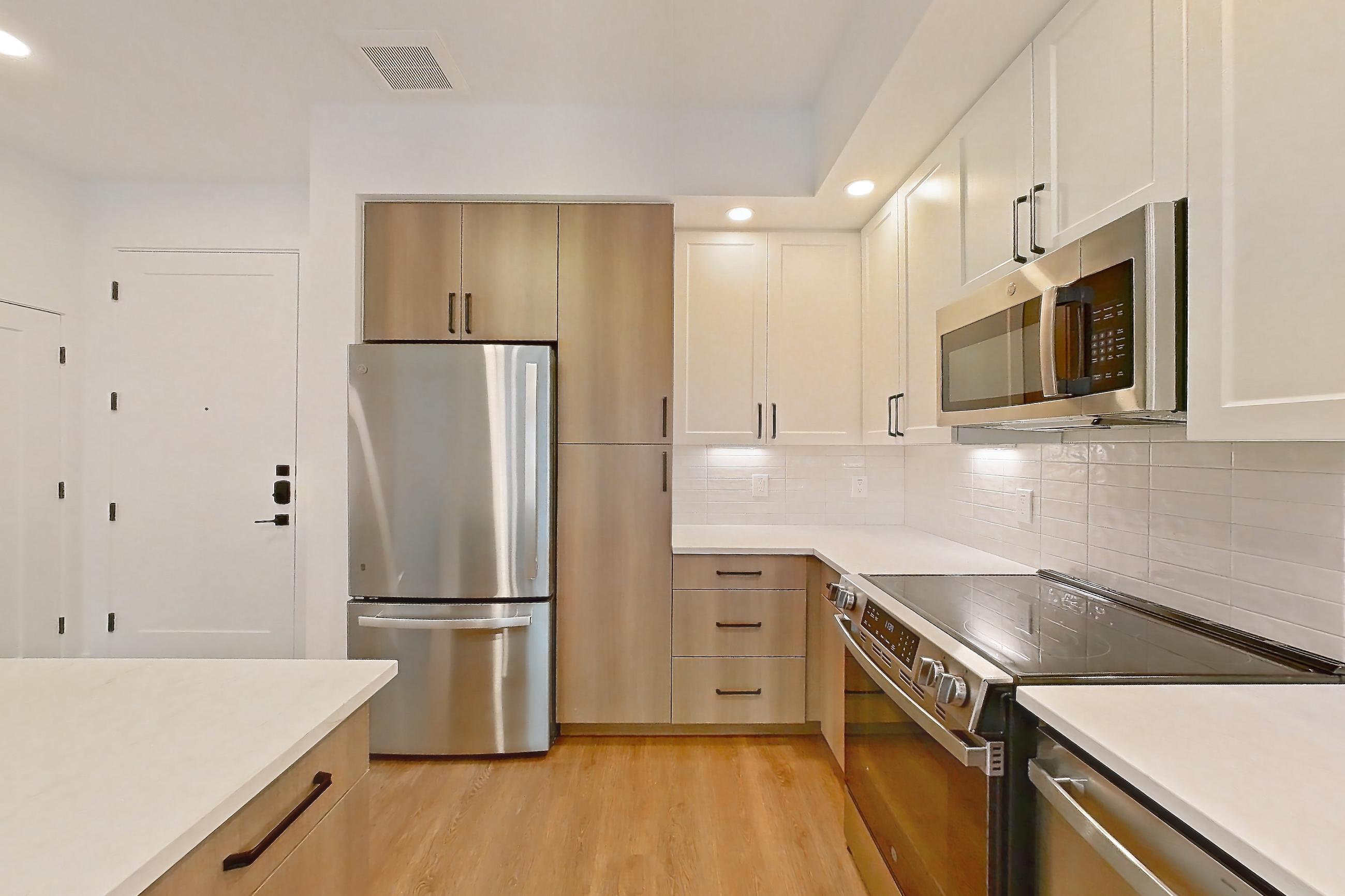 Kitchen with black appliances, dishwasher, electric range, light stone countertops, light wood-finish flooring, oven/range, and stainless steel appliances, Apartment 403 at The Watson