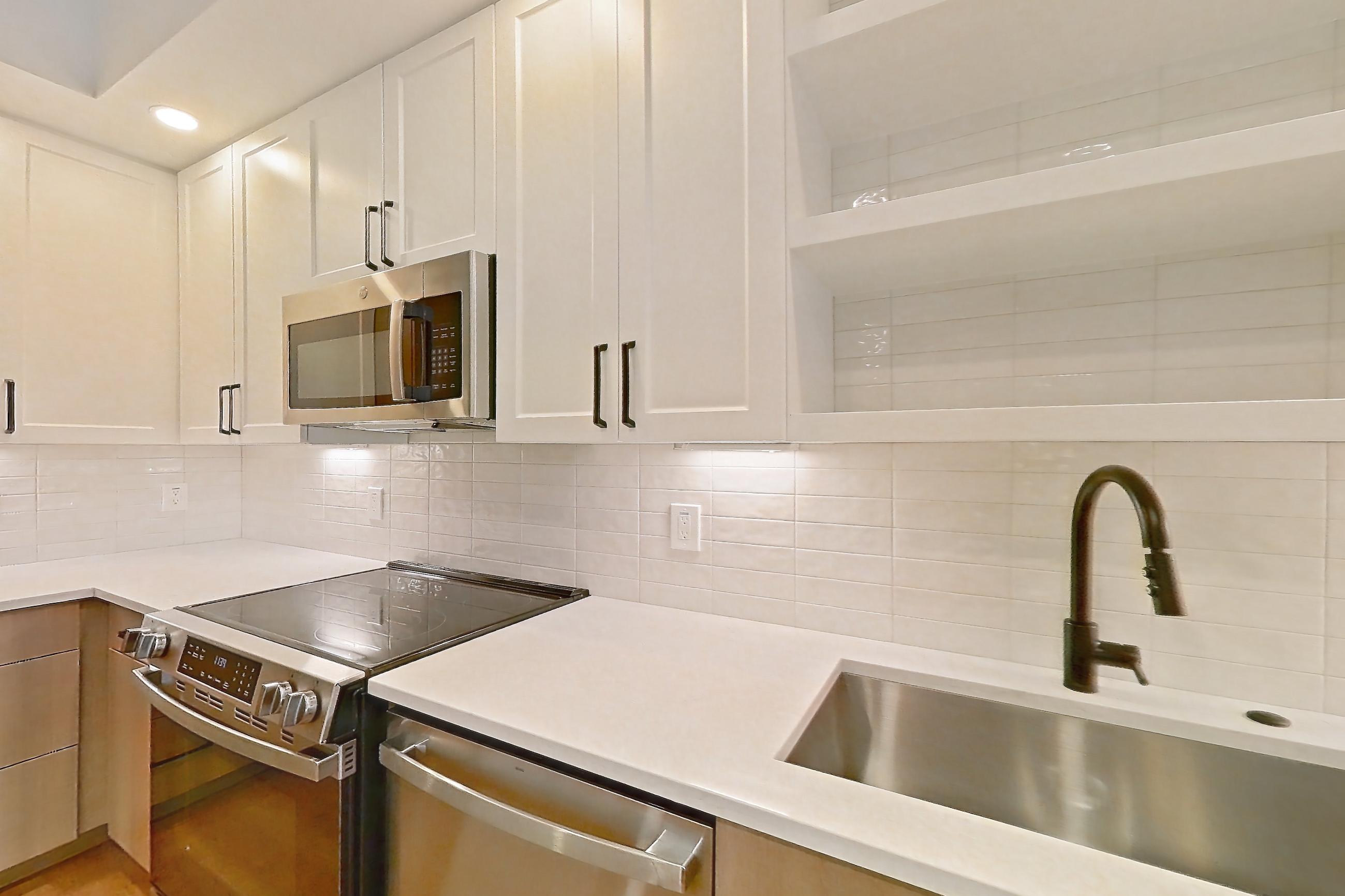 Kitchen with black appliances, dishwasher, electric range, light stone countertops, light wood-finish flooring, oven/range, and stainless steel appliances, Apartment 403 at The Watson