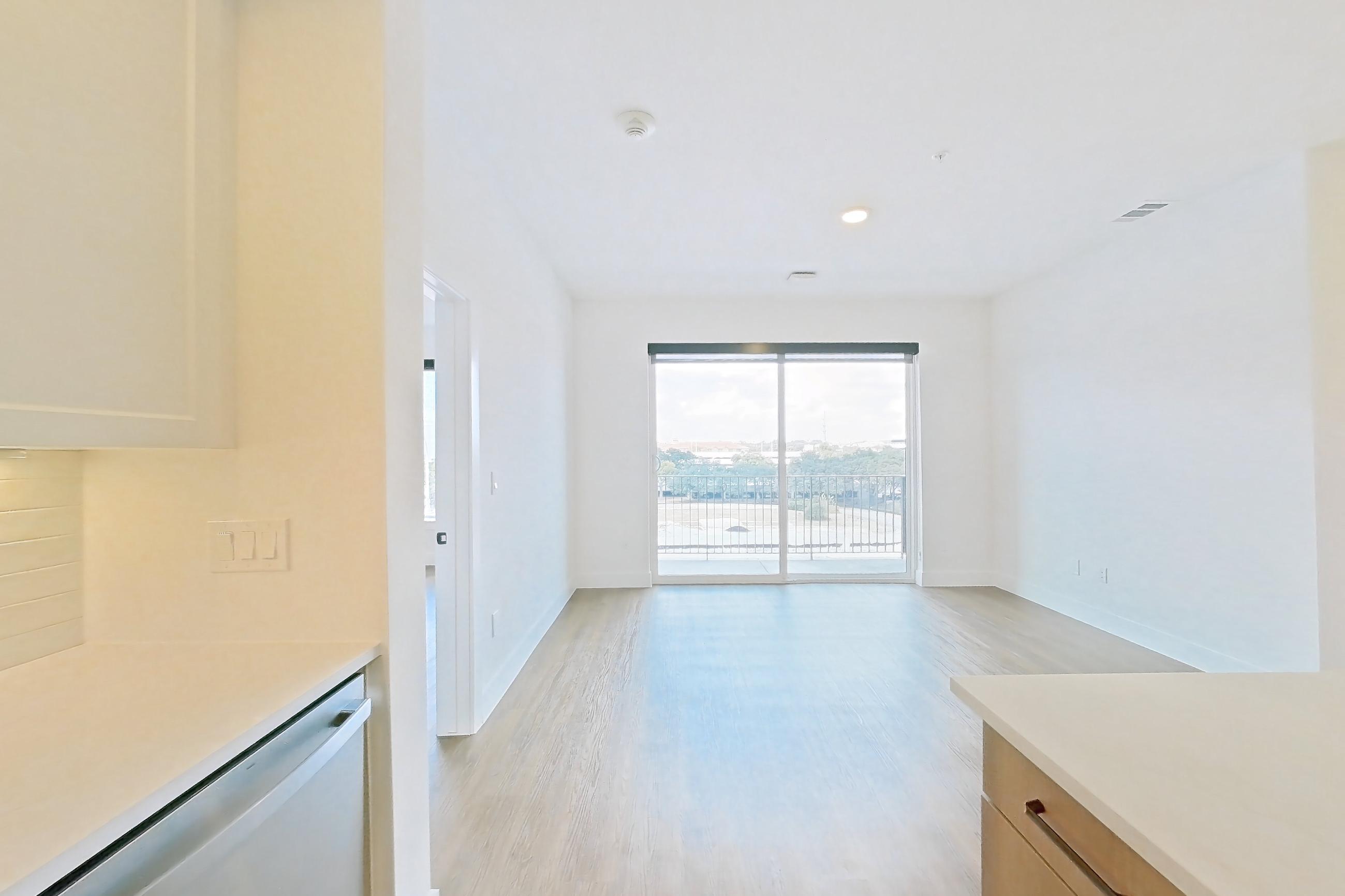 Kitchen with black appliances, dishwasher, electric range, light stone countertops, light wood-finish flooring, oven/range, and stainless steel appliances, Apartment 404 at The Watson