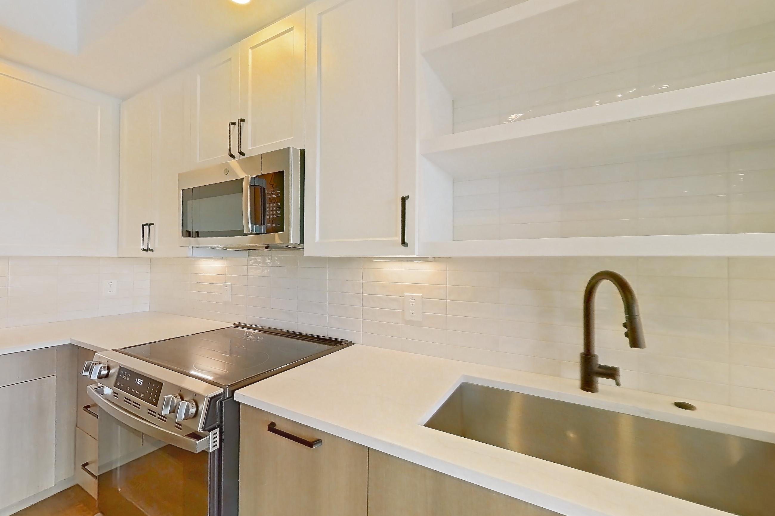 Kitchen with black appliances, dishwasher, electric range, light stone countertops, light wood-finish flooring, oven/range, and stainless steel appliances, Apartment 404 at The Watson