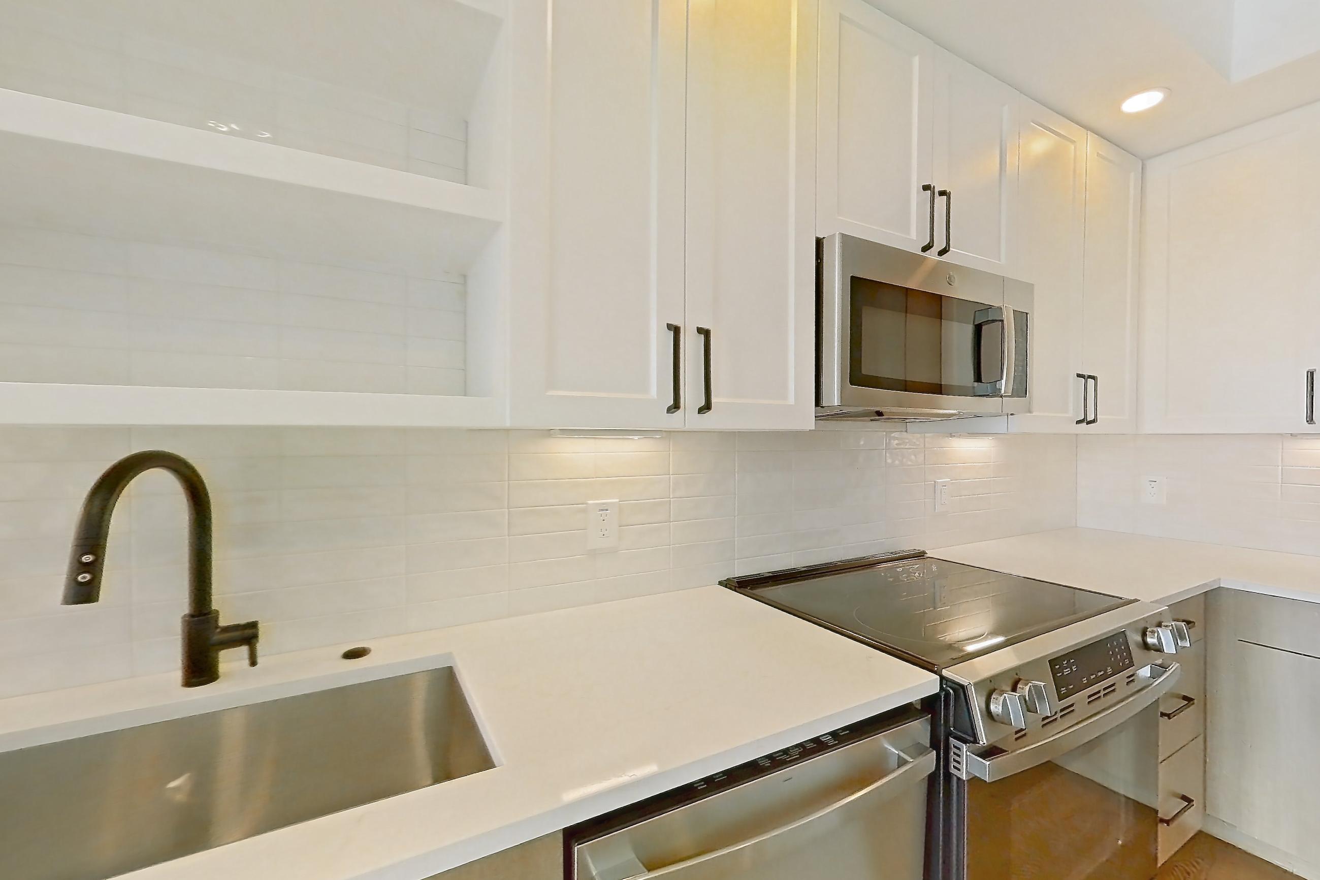 Kitchen with dishwasher, light stone countertops, light wood-finish flooring, and stainless steel appliances, Apartment 406 at The Watson
