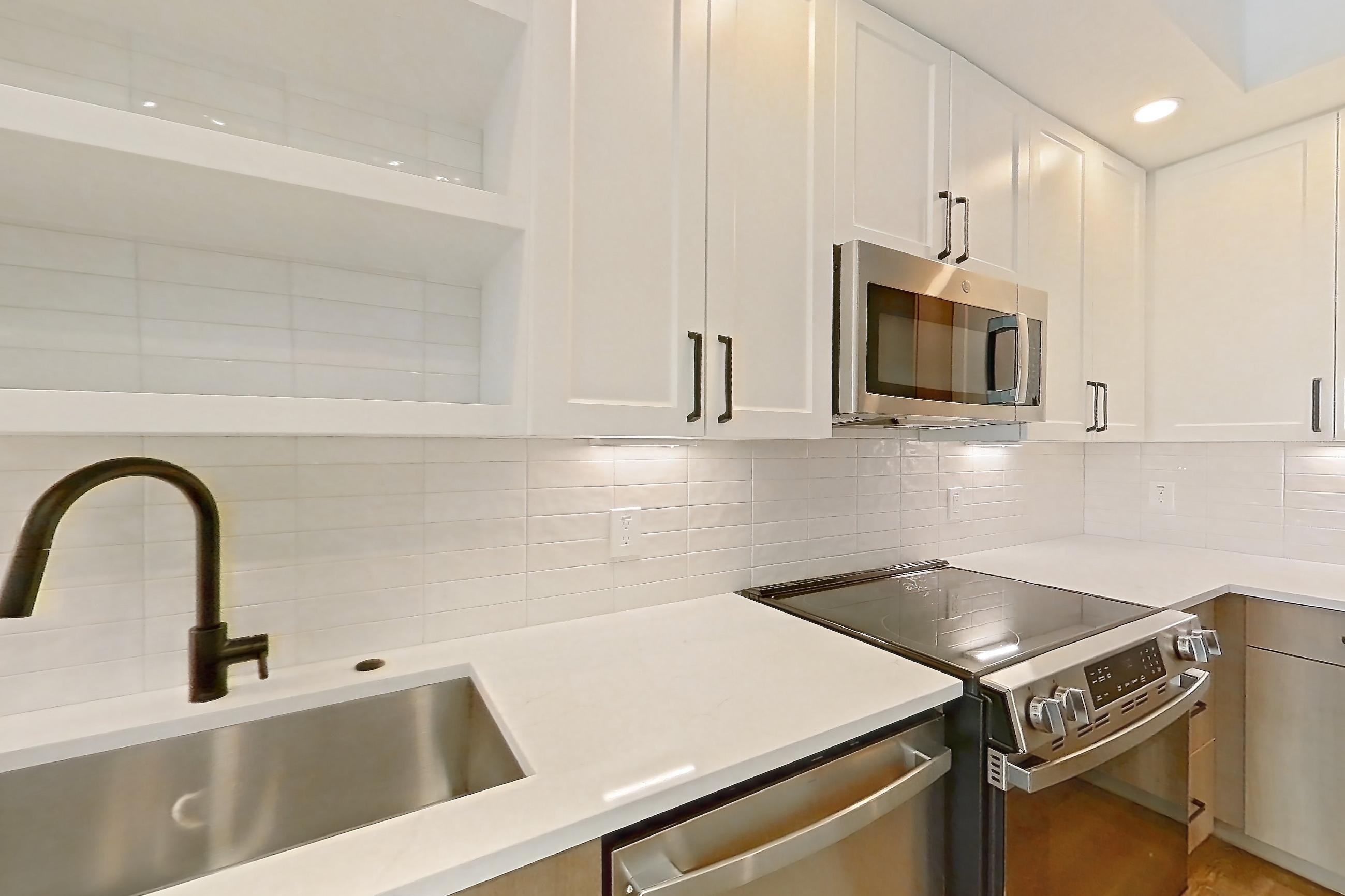 Kitchen with dishwasher, light stone countertops, light wood-finish flooring, and stainless steel appliances, Apartment 407 at The Watson