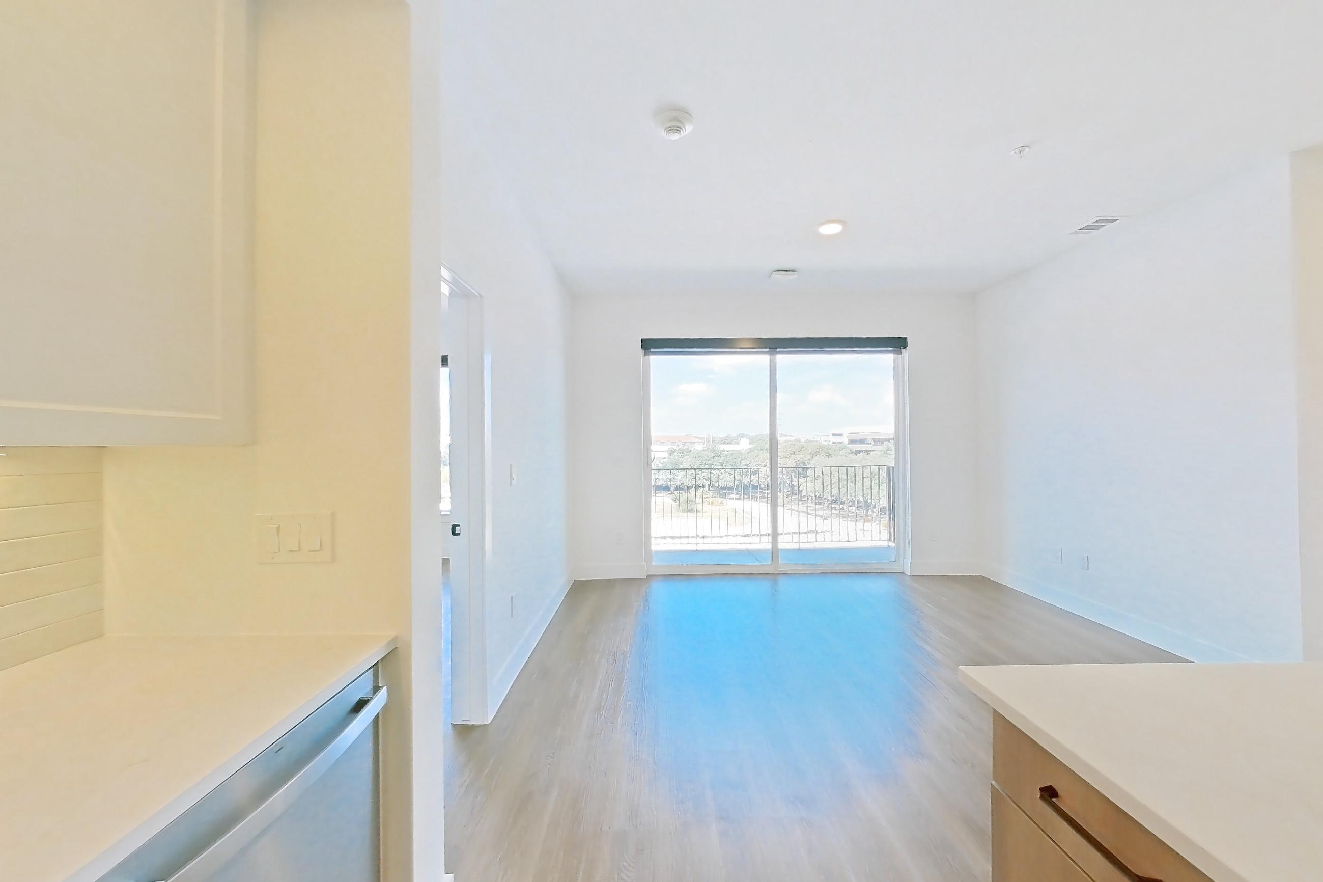 Kitchen with black appliances, dishwasher, electric range, light stone countertops, light wood-finish flooring, oven/range, and stainless steel appliances, Apartment 408 at The Watson