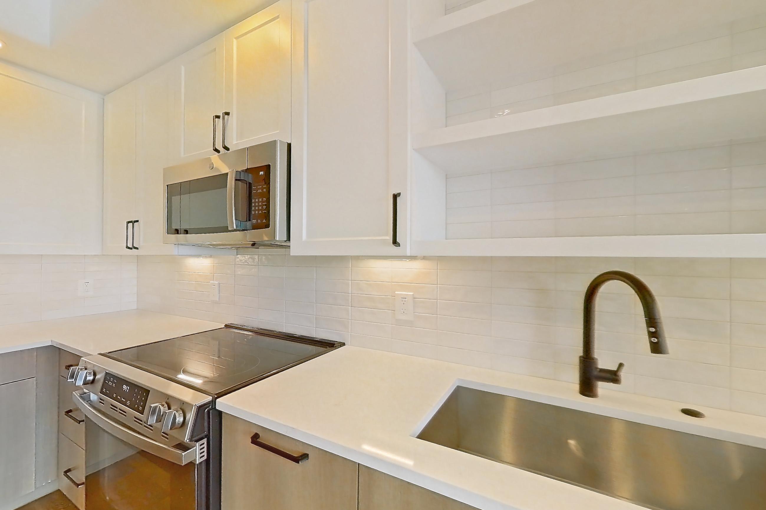 Kitchen with black appliances, dishwasher, electric range, light stone countertops, light wood-finish flooring, oven/range, and stainless steel appliances, Apartment 408 at The Watson