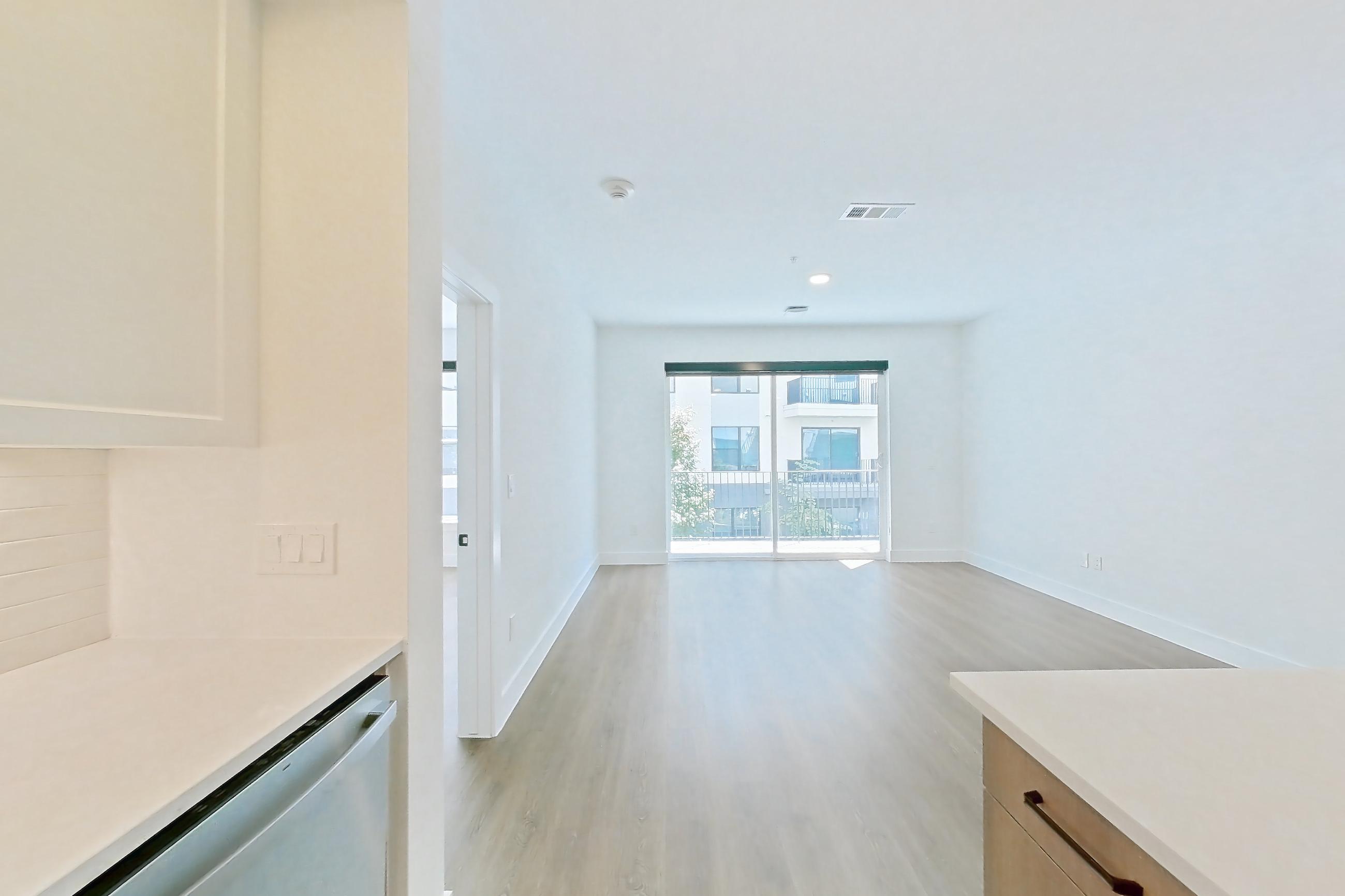 Kitchen with dishwasher, light stone countertops, light wood-finish flooring, and stainless steel appliances, Apartment 409 at The Watson