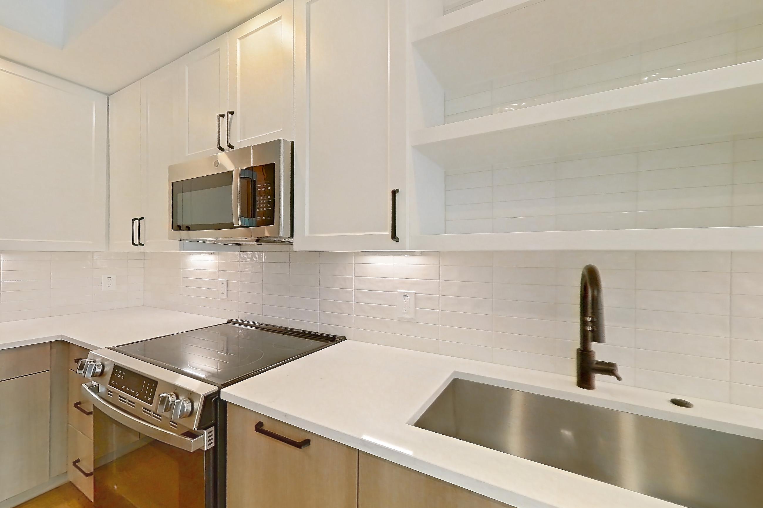 Kitchen with dishwasher, light stone countertops, light wood-finish flooring, and stainless steel appliances, Apartment 409 at The Watson