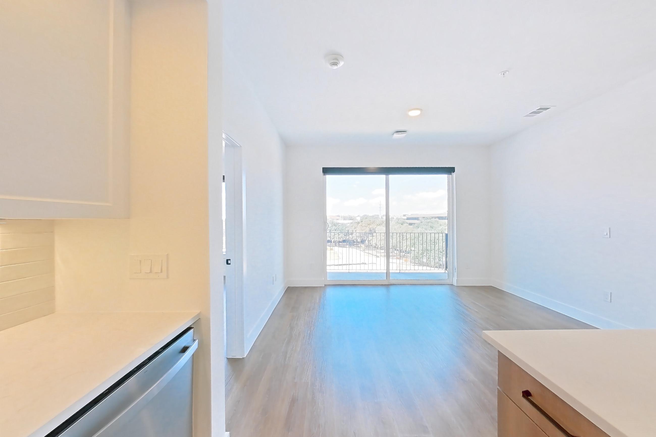 Kitchen with dishwasher, light stone countertops, light wood-finish flooring, and stainless steel appliances, Apartment 410 at The Watson