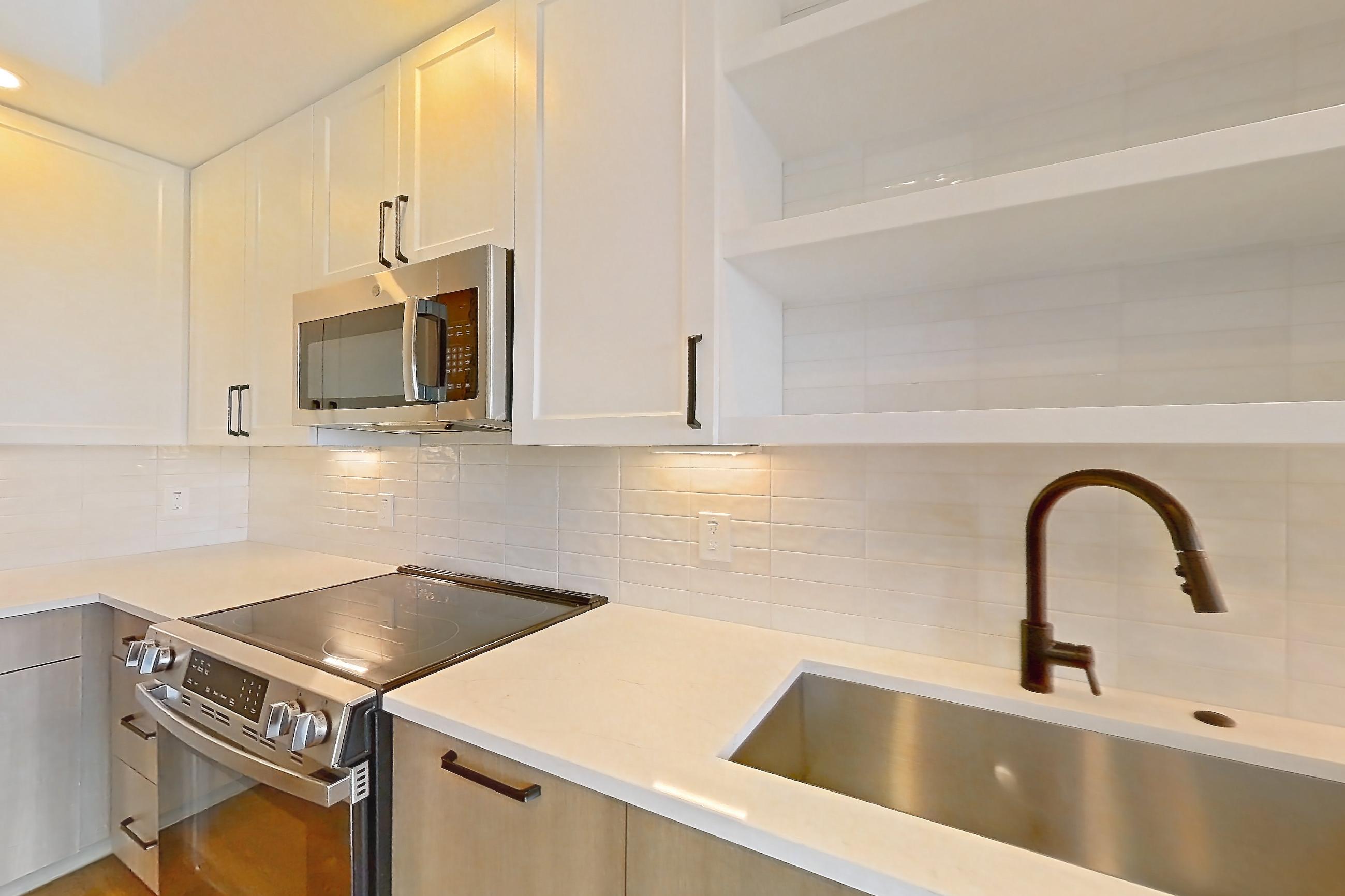 Kitchen with dishwasher, light stone countertops, light wood-finish flooring, and stainless steel appliances, Apartment 410 at The Watson